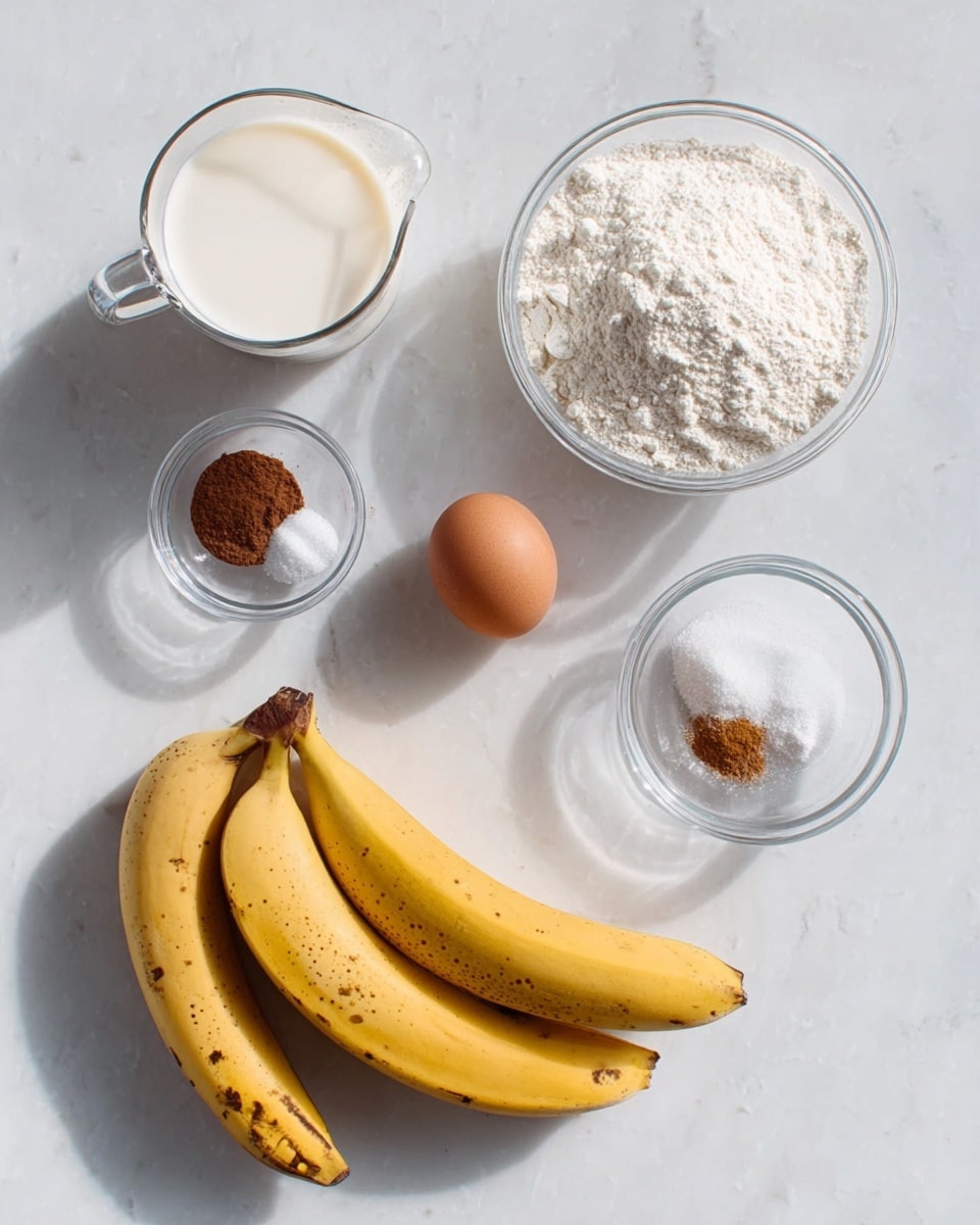 A flat lay image shows six ingredients arranged on a white marbled surface. At the top left, there is a clear glass measuring cup filled with milk. Next to it, in the middle top, a clear glass bowl is full of white flour. On the top right, a smaller clear glass bowl has three spices: brown cinnamon, white salt, and white powdered sugar. Below the flour bowl, there is a clear glass bowl holding a single brown egg. On the right side of the image, two yellow bananas with some brown spots lie close to each other. The bright natural light and soft shadows highlight the textures of each ingredient. Photo taken with an iphone --ar 4:5 --v 7