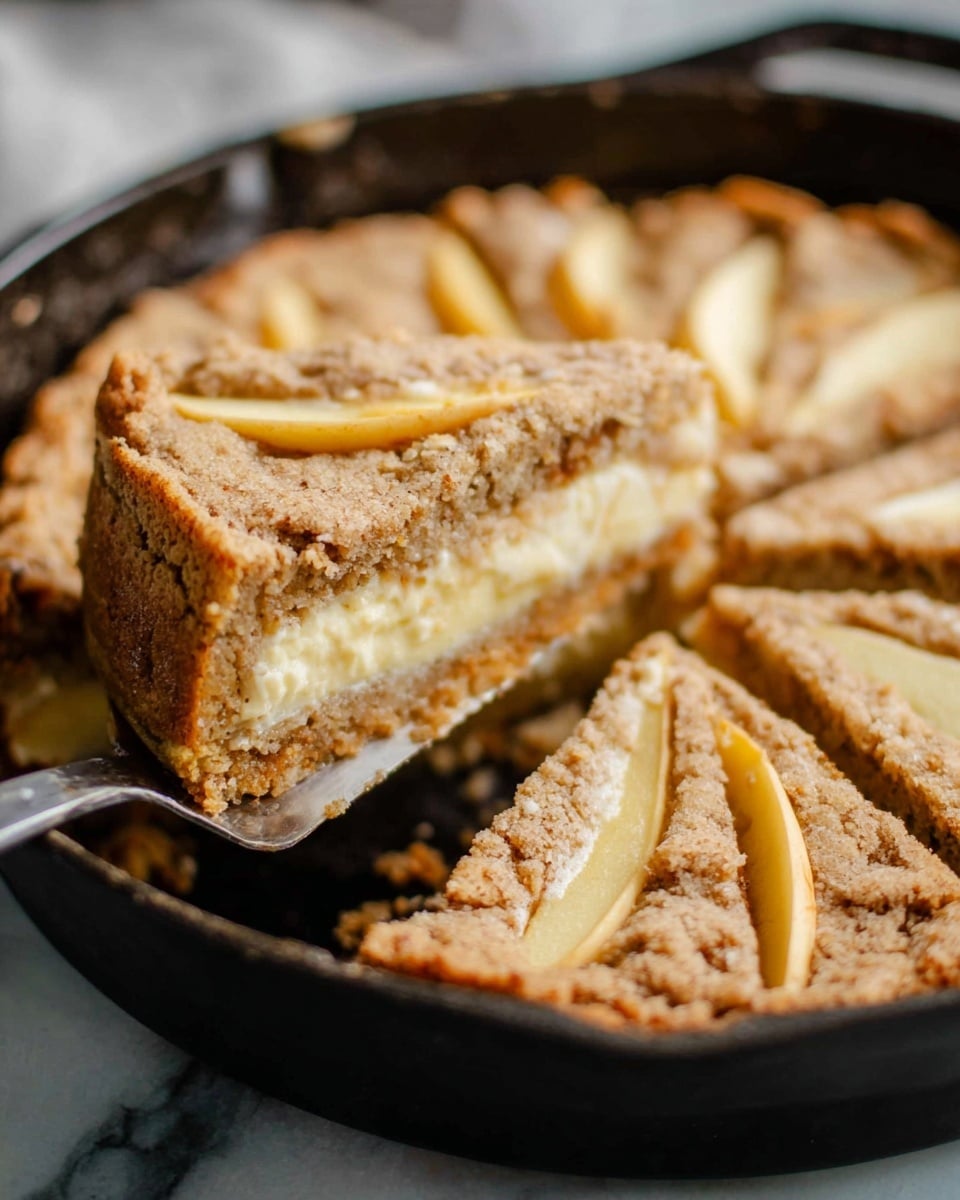 The image shows a close-up view of a round cake with visible layers in a black cast iron pan on a white marbled surface. The cake is cut into slices, and a slice is being lifted by a silver spatula. The cake has three layers: a light brown crumbly base, a thick middle layer of creamy pale yellow filling, and a top layer made of textured, slightly rough brown cake. Thin slices of fruit, likely apple, are visible on the top layer, arranged in a slightly curved pattern. The cake looks moist and homemade with a rustic texture. Photo taken with an iphone --ar 4:5 --v 7
