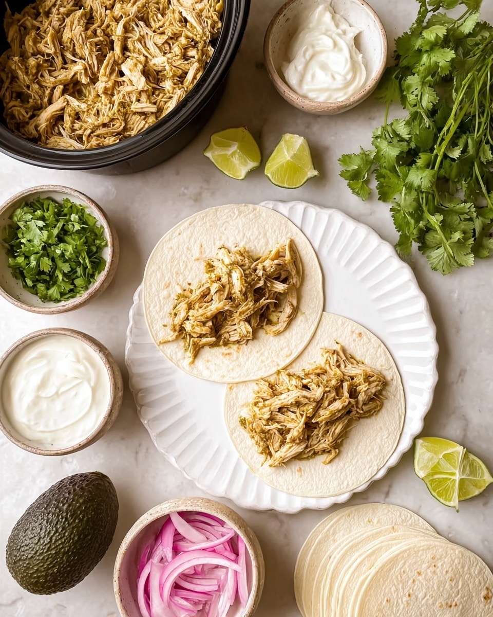Two soft white tortillas lie on a white scalloped plate, each topped with a layer of shredded light brown cooked chicken with a slight green seasoning mixed in. To the top left, a black pot is filled with more shredded chicken, showing a rough texture. Below, a whole dark green avocado is placed on a white marbled surface, next to a small bowl of smooth white sour cream. Another small bowl filled with bright green fresh cilantro leaves is nearby, and a bowl of thinly sliced pink and white pickled onions adds a pop of color. To the right, several white tortillas are stacked, and lime wedges, both halved and quartered, rest on the white marbled surface. A small bunch of fresh cilantro leaves sits on the upper right corner. The photo taken with an iphone --ar 4:5 --v 7