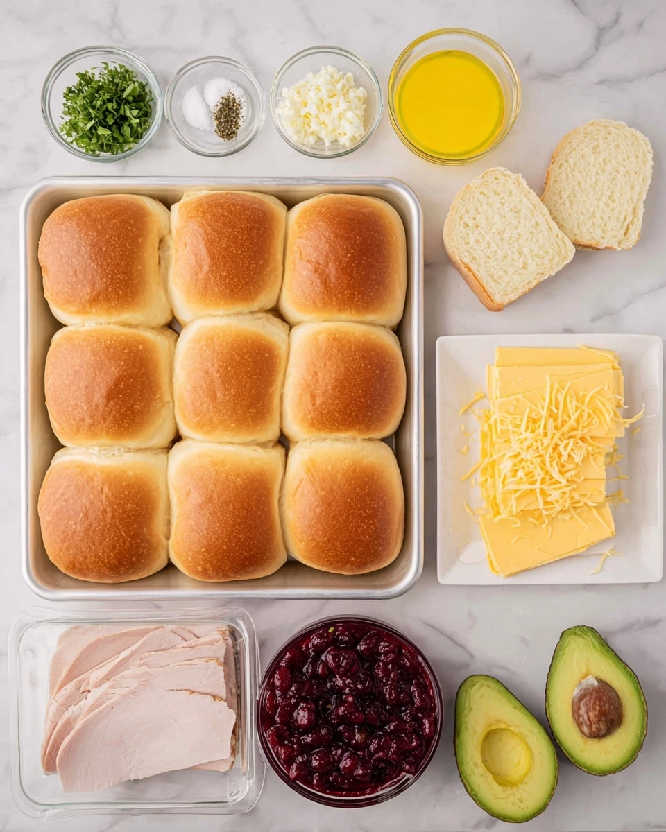 The image shows a metal baking tray with 20 golden brown slider buns arranged in a 4 by 5 grid, each bun having a soft and slightly wrinkled top texture. Above the tray are four small clear glass bowls containing white salt, crushed black pepper, chopped yellow garlic, and chopped green herbs. To the right of the tray is a white bowl filled with shiny melted butter and below it, a white plate stacked with five slices of pale yellow cheese with herbs. Below the buns are a clear container holding several slices of pale pink turkey meat, a white bowl with red chunky cranberry sauce, and two halves of a ripe green avocado with dark seeds. All items are set on a white marbled surface. Photo taken with an iphone --ar 4:5 --v 7