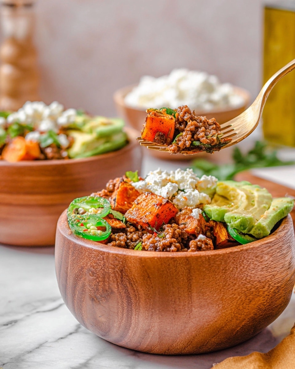 The image shows a wooden bowl filled with several layers of food. The bottom layers appear to be cooked ground meat, rich brown and crumbly, topped with chunks of orange roasted sweet potato with a slightly charred texture. On top of this, there are bright green slices of jalapeño peppers and diced avocado, creamy and light green. There is also a layer of white cottage cheese adding a soft, curd-like texture. A gold fork is lifting a mix of the meat, sweet potato, avocado, and cottage cheese from the bowl. In the blurred background, another identical bowl filled with similar ingredients, a white bowl with cottage cheese, and a bottle of olive oil are visible. The scene is set on a white marbled texture. Photo taken with an iphone --ar 4:5 --v 7