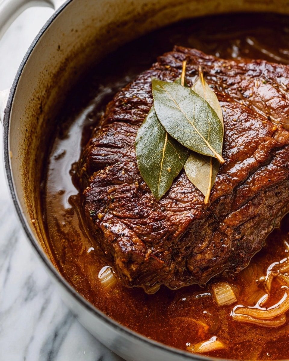 A large piece of cooked beef with a dark brown, textured surface sits in a white pot filled with rich, brown sauce and visible small chunks of onions. Two light brown bay leaves rest on top of the beef, adding a thin, dry texture. The sauce looks thick and glossy, pooling around the beef inside the pot, which is set on a white marbled surface. photo taken with an iphone --ar 4:5 --v 7