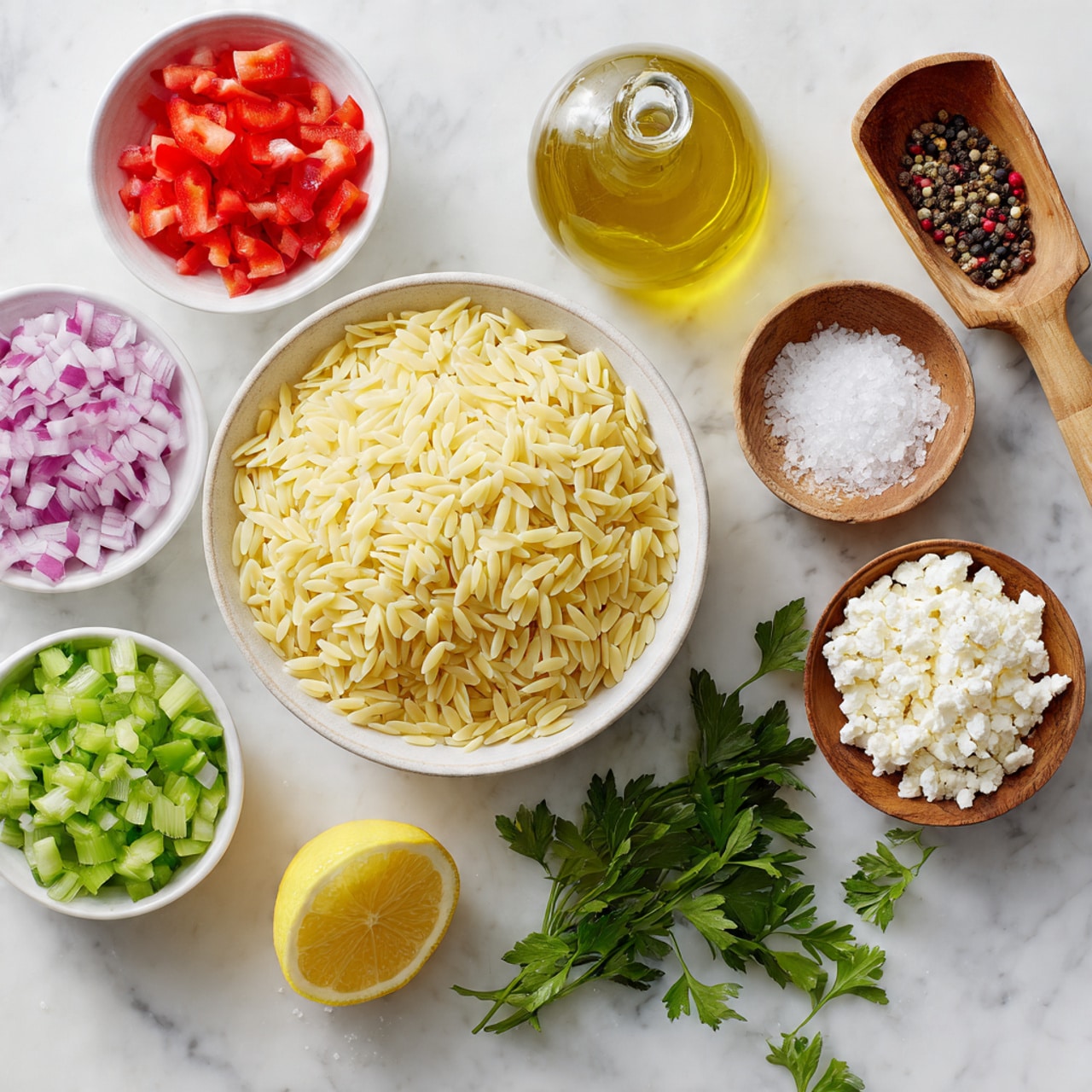 The image shows a white bowl filled with pale yellow orzo pasta at the center, surrounded by smaller white bowls holding chopped red bell peppers, green celery, finely diced red onions, and white crumbled cheese. To the right, there is a clear glass bottle with yellow olive oil, and two small round wooden bowls contain coarse white salt with a small wooden scoop and a mix of black and red peppercorns with a similar scoop. Below, a halved yellow lemon and green parsley sprigs rest directly on the white marbled surface. The setup is bright and clean with clear texture contrasts between the smooth pasta, crisp vegetables, and rough salt crystals, photo taken with an iphone --ar 4:5 --v 7