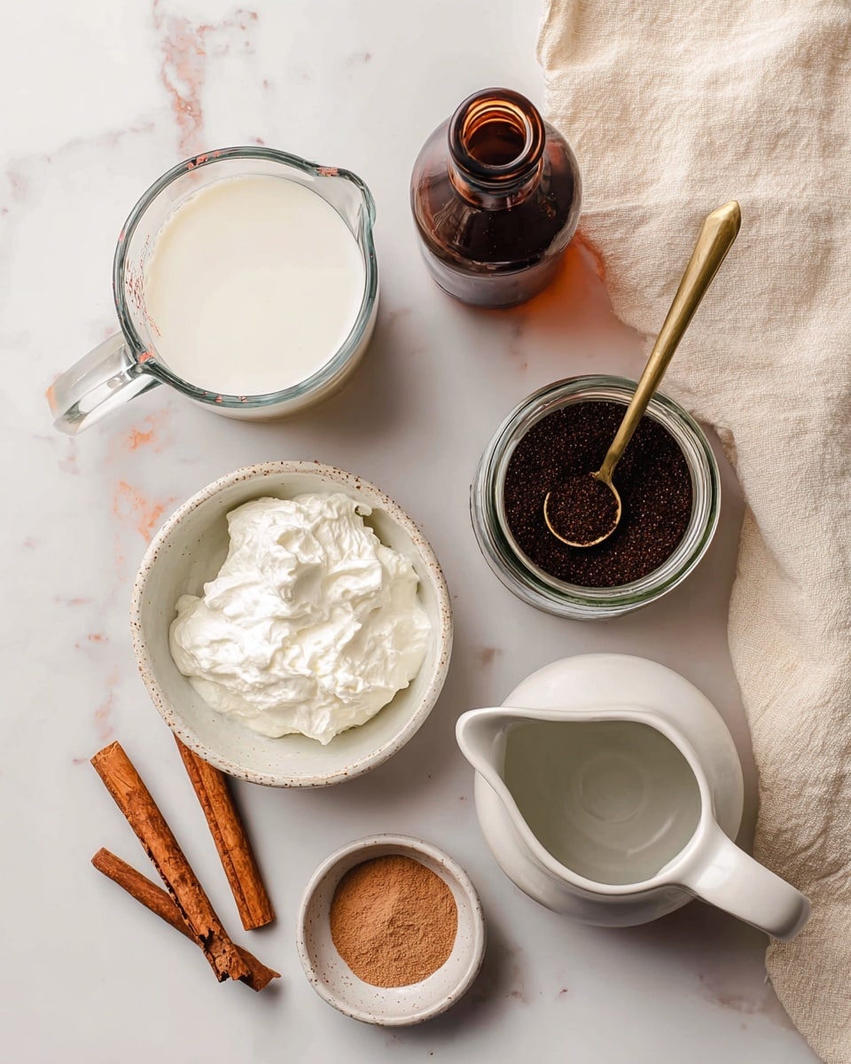 The image shows an overhead view of ingredients arranged on a white marbled surface. On the top left, there is a glass measuring cup filled with white milk. Next to it, on the top middle, is a dark brown glass bottle with a narrow neck. To the right, there is a small glass jar filled with dark brown coffee grounds and a gold measuring spoon resting inside. Below the coffee jar, there is a smooth white bowl holding whipped cream or a similar white creamy substance. To the right of this bowl, there is a white ceramic pitcher with a spout. Below the pitcher, a small white bowl contains a light brown ground spice, likely cinnamon. Two brown cinnamon sticks lie diagonally on the bottom left side. A cream-colored cloth is partially visible on the right side of the image. The arrangement is neat and organized, and the photo was taken with an iphone --ar 4:5 --v 7