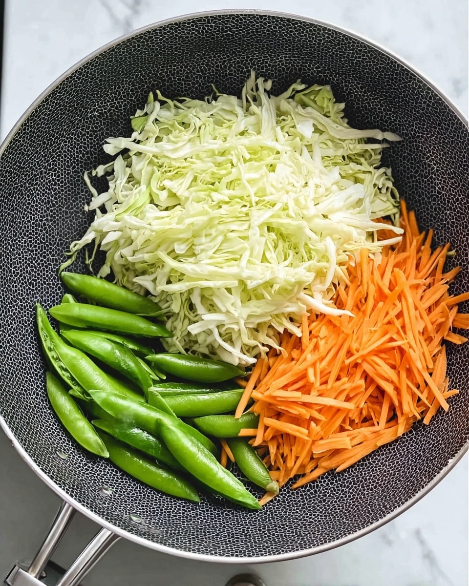 A round pan with a black honeycomb pattern shows three groups of vegetables arranged inside. At the top is a large pile of thinly shredded white cabbage with a light green tint, on the right are bright green snap peas with smooth, shiny surfaces, and at the bottom left, there are thin orange carrot sticks laid roughly parallel. The pan has a metal handle on the left side, and the background is a white marbled surface. photo taken with an iphone --ar 4:5 --v 7