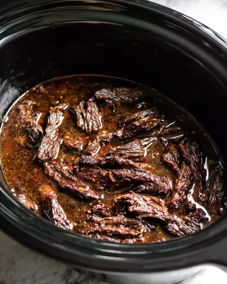 The image shows a slow cooker filled with dark brown, cooked strips of meat sitting in a rich, thick brown sauce. The meat has a slightly shiny, tender texture, and the sauce covers the bottom of the cooker, surrounding the meat. The slow cooker itself is black and round, with a shiny surface, and the inside is filled mostly with the meat and sauce mixture. The photo is taken from above, focusing on the juicy meat pieces and sauce, with a white marbled surface visible under the slow cooker. photo taken with an iphone --ar 4:5 --v 7