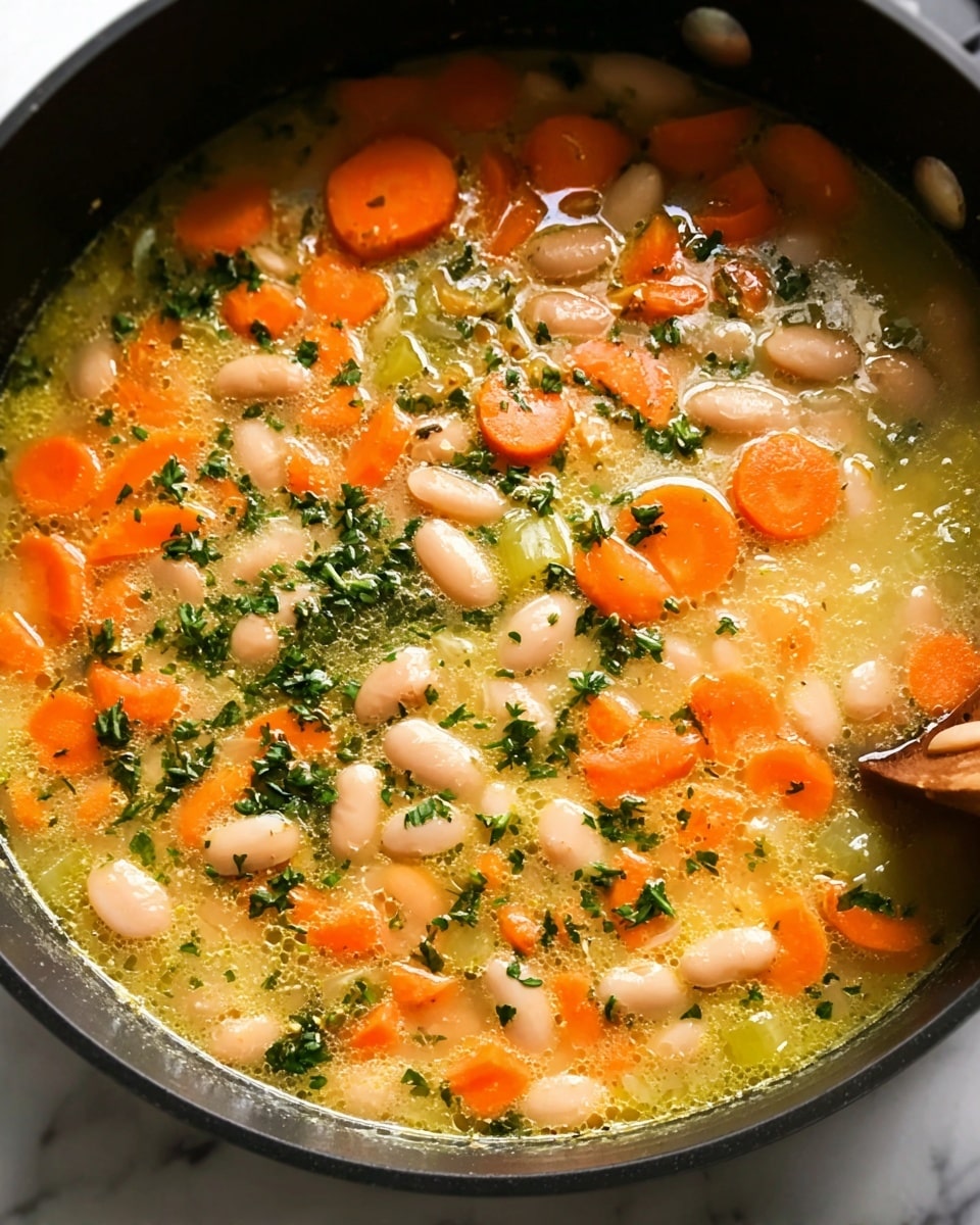 This image shows a close-up of a soup in a black pan on a white marbled surface. The soup has multiple layers of orange carrot slices, white beans, and small green celery pieces floating in a light yellow broth. Finely chopped green herbs are sprinkled throughout, adding color and texture. A wooden spoon is partially visible on the right side of the pan, slightly covered by the soup. Photo taken with an iphone --ar 4:5 --v 7