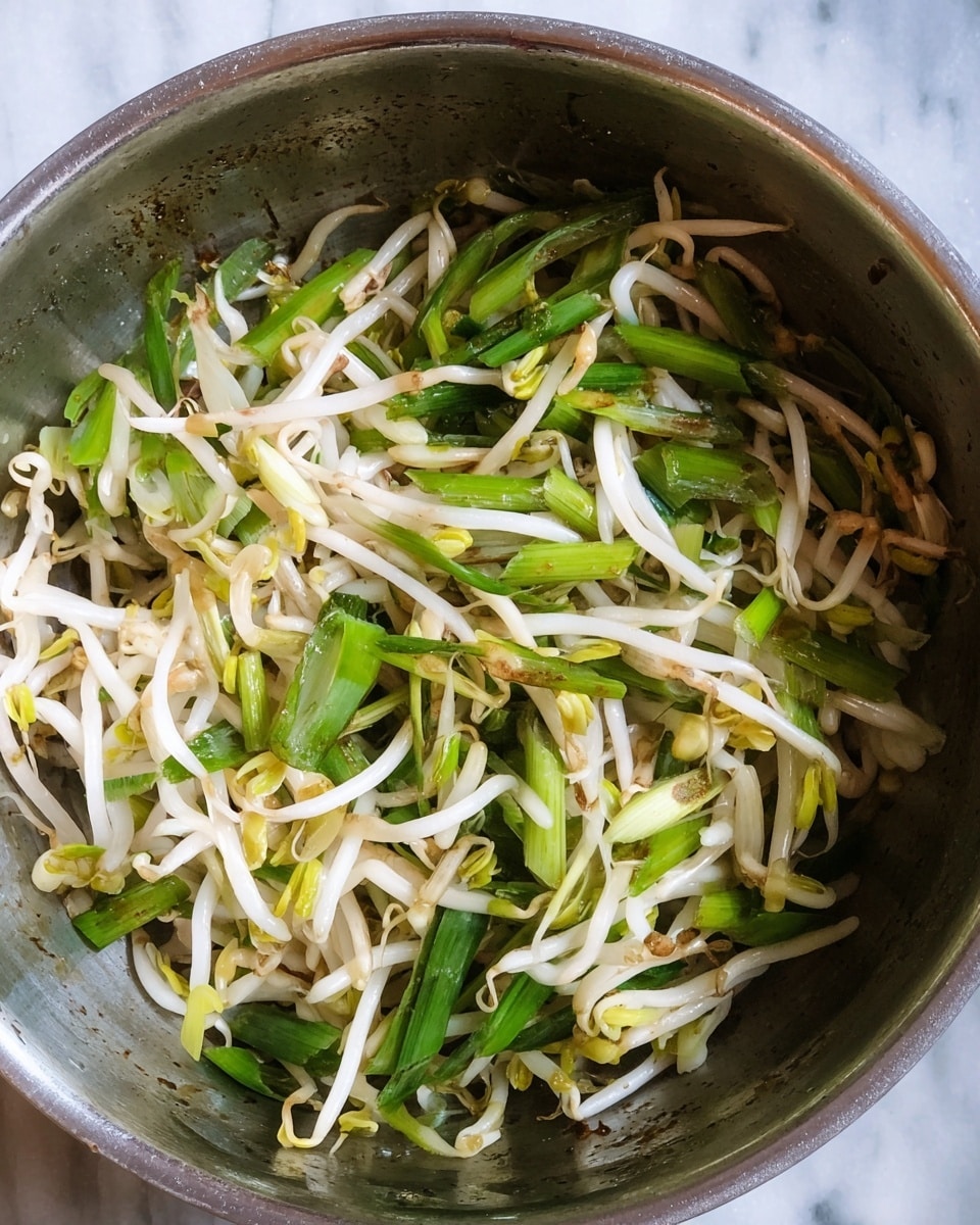 Inside a round metal pan, a mix of two layers fills the space: the bottom layer consists of thin, white bean sprouts with a slight shine and some brownish tips, scattered unevenly; the top layer shows thick slices of fresh green onions, ranging from light to dark green, distributed across the sprouts. The pan surface shows small marks and a bit of oil residue, adding a natural texture to the image. The background is a white marbled surface. photo taken with an iphone --ar 4:5 --v 7