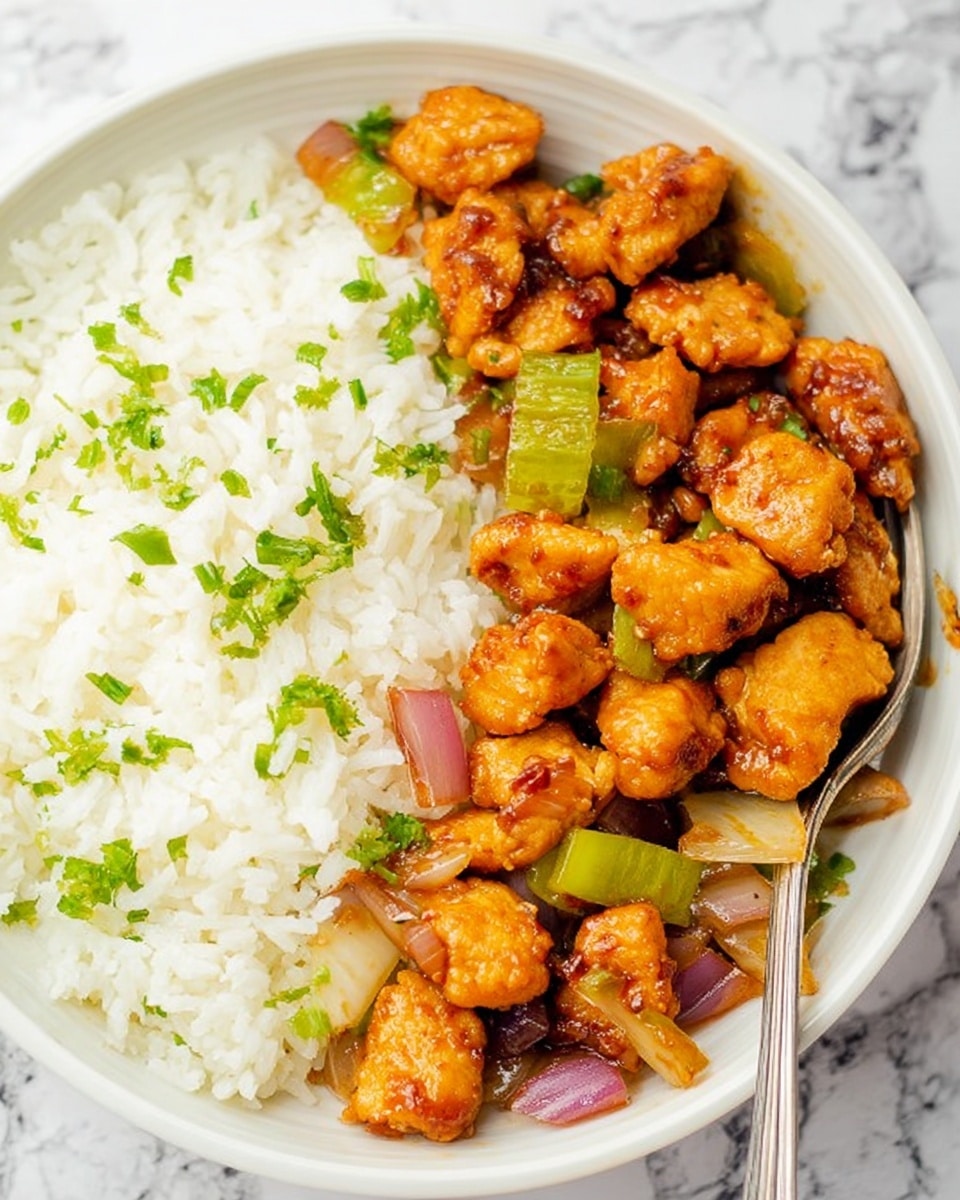 A white bowl filled with a vibrant chicken stir-fry dish featuring many small pieces of golden-brown chicken layered throughout. Mixed among the chicken are chunks of bright green bell peppers and slices of pinkish-red onions, all coated in a shiny, thick brown sauce that adds a glossy texture to the dish. The colors and textures create a lively contrast with the white bowl and the white marbled surface underneath. photo taken with an iphone --ar 4:5 --v 7