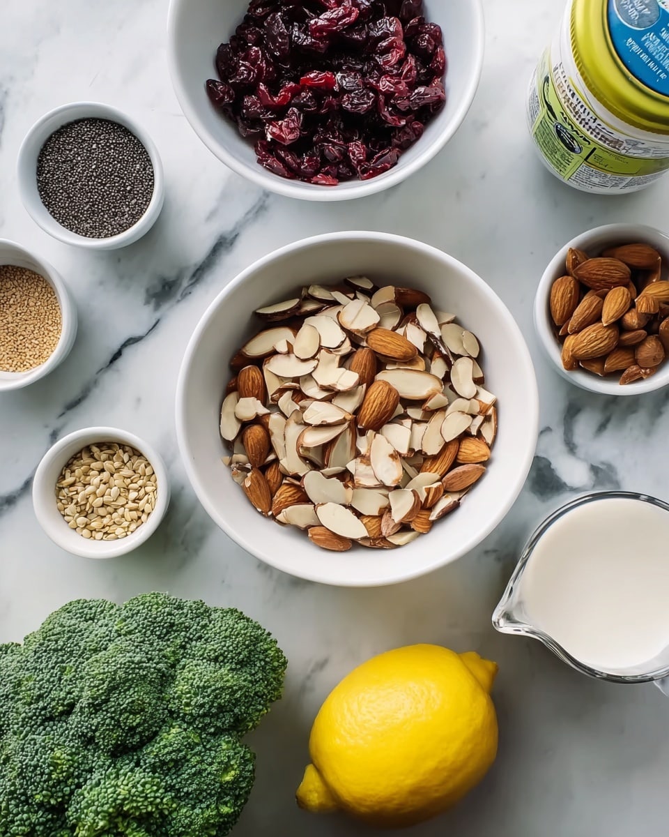 The image shows a flat lay of different food ingredients arranged on a white marbled surface. In the center is a white bowl filled with sliced almonds that are light brown and beige with a slightly rough texture. To the top left, there is another white bowl containing dark red dried cranberries with a wrinkled, shiny look. To the far right, a whole bright yellow lemon with a bumpy texture is placed near a blue and yellow jar. Below the lemon is a white measuring cup filled with a creamy liquid, likely milk. On the bottom left corner, there is a fresh green broccoli with a rough, bumpy texture. Surrounding the main bowl of almonds are smaller white bowls containing a variety of seeds or spices, including small black round seeds and a bowl with tan-colored seeds. A white container with a green label is partially visible near the broccoli. Photo taken with an iphone --ar 4:5 --v 7