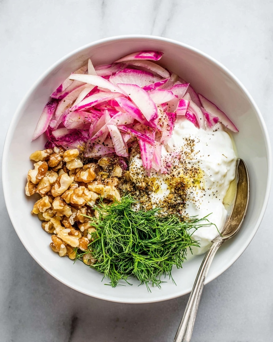A white bowl sits on a white marbled surface, filled with distinct layers of ingredients. The top left section has thin, pale pink and white strips of radish with purple edges. Below this is a small pile of chopped walnuts in a light brown color. To the right of the radish and walnuts is a portion of bright green fresh dill. Near the center, there is a dollop of white creamy yogurt or sour cream with a smooth texture. A sprinkle of black pepper and other seasoning sits slightly overlapping the yogurt and walnuts. A silver spoon rests inside the bowl on the right side. photo taken with an iphone --ar 4:5 --v 7