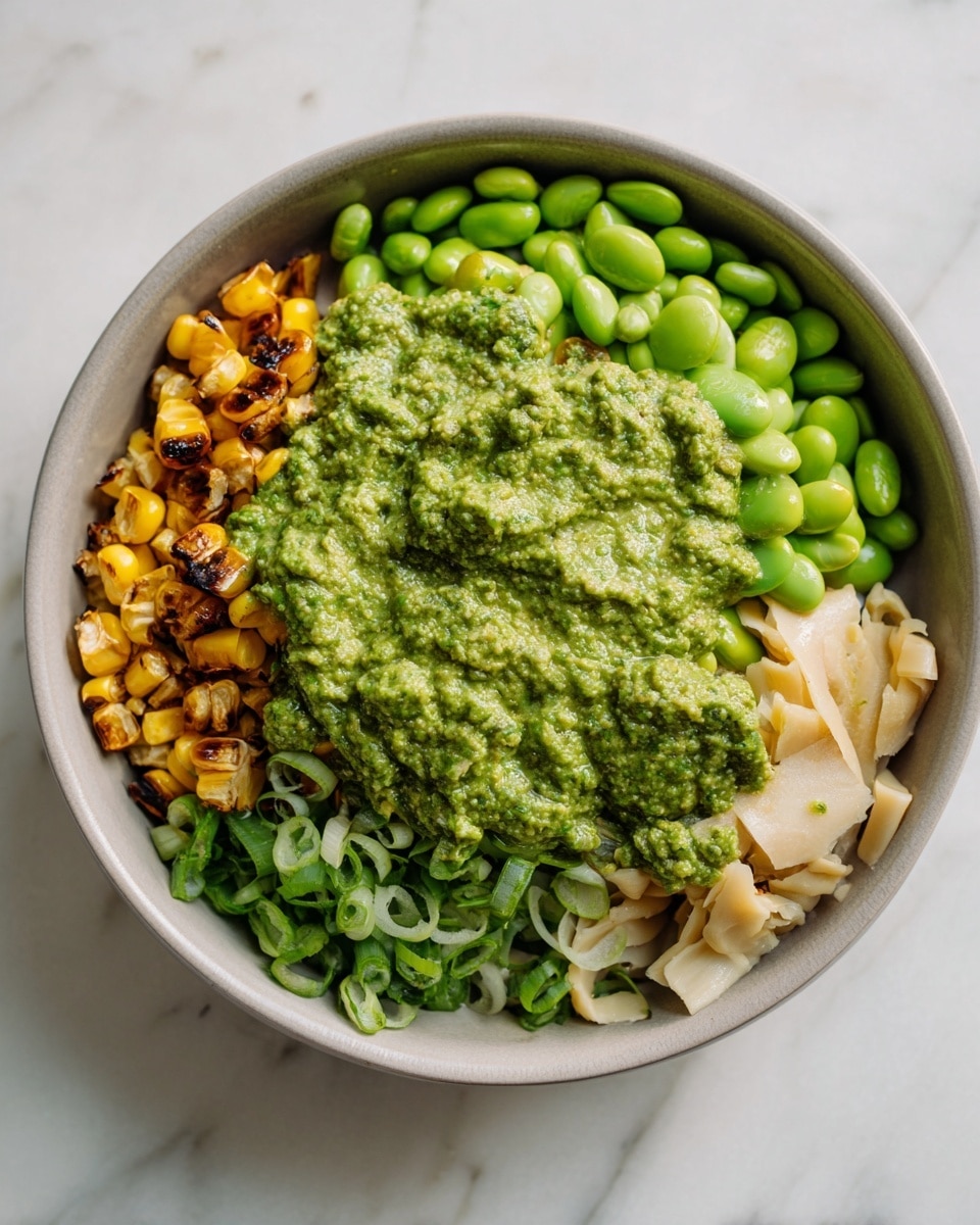 A close-up view of a creamy white dip with a thick texture in a round beige bowl sitting on a white marbled surface. The dip has small colorful chunks of red, yellow, and green vegetables scattered throughout, with green herbs sprinkled on top. There are a few whole white crackers dipped and resting inside on the surface of the dip as well as some crackers placed around the bowl. The dip also has some grated cheese and a drizzle of golden oil, adding a shiny and rich look to the top. photo taken with an iphone --ar 4:5 --v 7