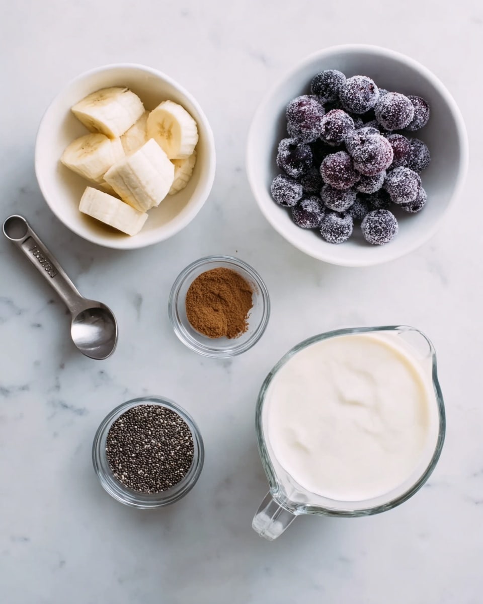 The image shows several small white bowls and a measuring cup on a white marbled surface. One white bowl contains pieces of peeled banana, another has frozen dark purple blueberries covered with a light frost. A small white bowl holds chia seeds, and a tiny clear glass container has ground cinnamon with a warm brown color. There is a clear glass bowl filled with creamy white yogurt, and a metal measuring cup is filled with a white liquid, likely milk. Each item is neatly placed with soft natural light highlighting the different textures and colors of the ingredients. Photo taken with an iphone --ar 4:5 --v 7