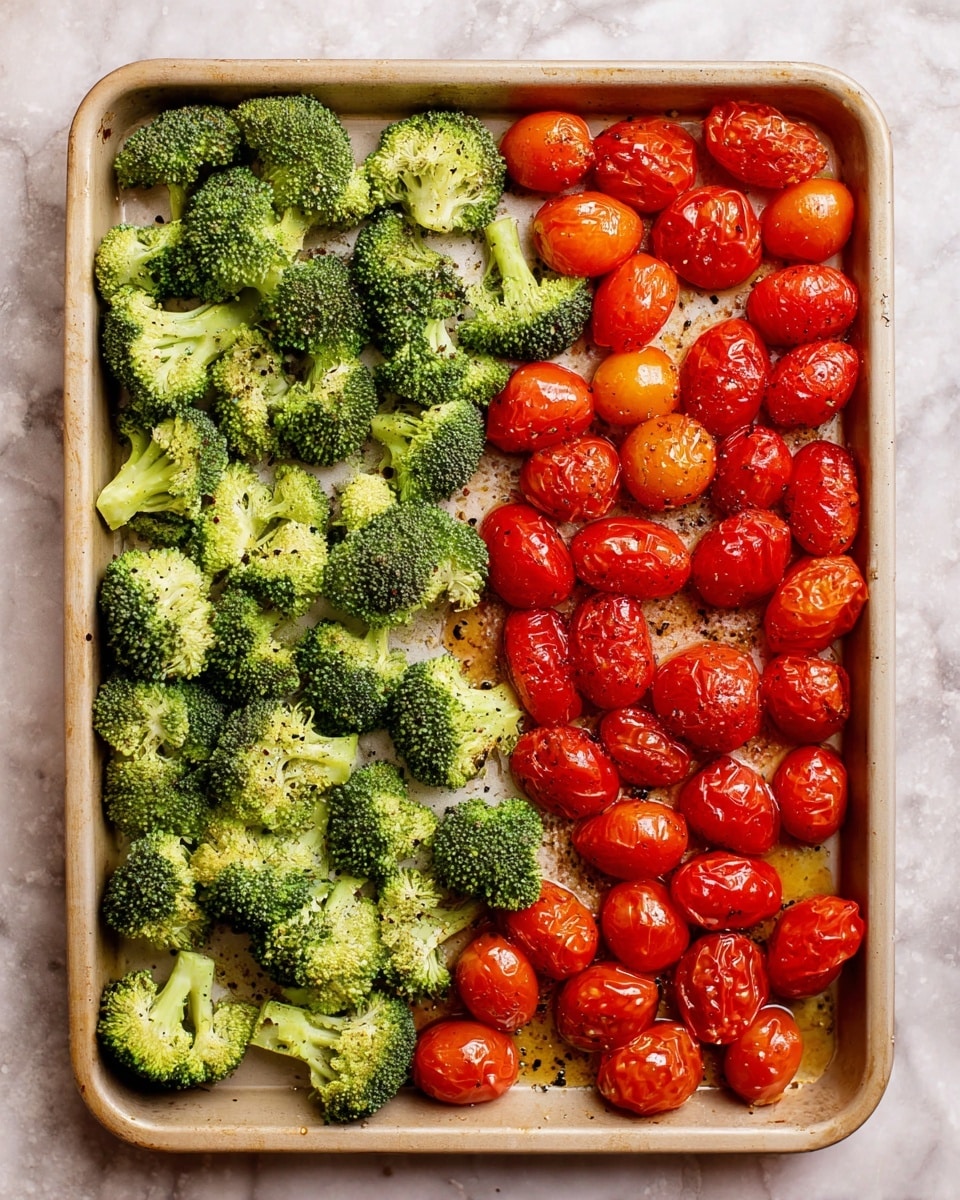 A baking tray filled with two layers of vegetables laid side by side, the left side has bright green broccoli florets with a fresh, rough texture, while the right side is covered with halved cherry tomatoes, showing a shiny red surface with visible seeds and a slightly wet look. Both vegetables are lightly seasoned with black pepper and oil droplets scattered across them. The tray has a warm beige color and sits on a white marbled textured surface. photo taken with an iphone --ar 4:5 --v 7