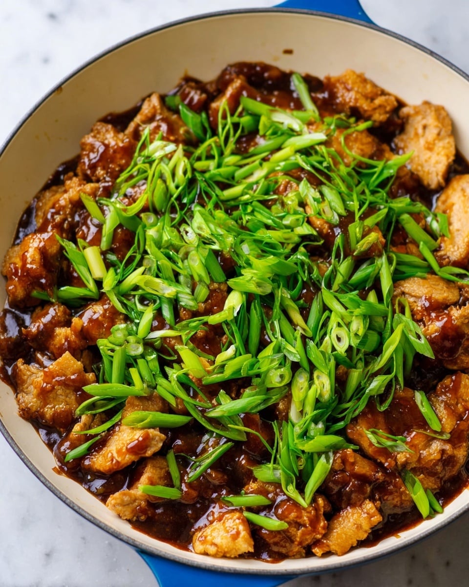 A white skillet filled with three main layers: the bottom layer shows pieces of light golden brown cooked meat with a crispy edge, the middle layer is covered with a thick, shiny dark brown sauce that coats some meat pieces, and the top layer consists of fresh, bright green chopped scallions scattered evenly on top. The skillet's handle is blue, and the dish sits on a white marbled surface. photo taken with an iphone --ar 4:5 --v 7