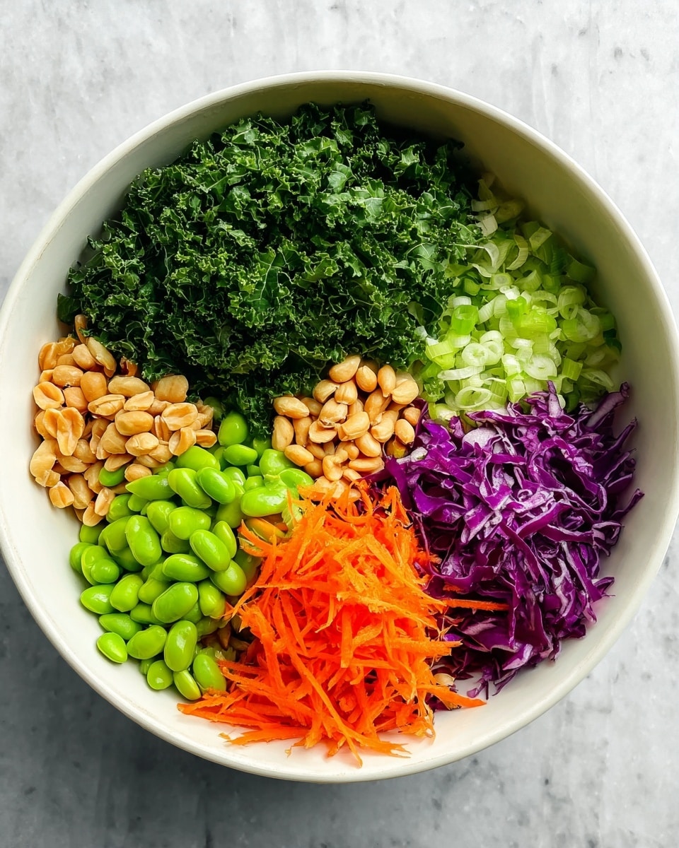 A white bowl holds six different ingredients, each arranged in a neat section. Starting from the top left, there is dark green curly kale leaves, next to it is finely chopped fresh green parsley. To the right of the parsley is a section of light green sliced green onions, followed by a portion of finely chopped purple cabbage. Below the cabbage is a pile of bright orange shredded carrots. To the left of the carrots and below the kale are vibrant green shelled edamame beans. Sitting above the edamame and next to the kale is a small pile of whole roasted peanuts, light brown in color. The bowl's contents are displayed on a white marbled surface. Photo taken with an iphone --ar 4:5 --v 7