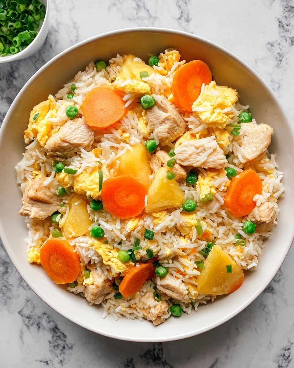 A black pan filled with a mix of long white cooked rice as the base layer, mixed with light yellow scrambled eggs in soft, small pieces. On top, there are light brown chicken pieces with a slightly peppered texture scattered evenly throughout. Bright orange carrot slices with ridged edges and chunks of yellow pineapple add color, along with small green peas and chopped green onions spread on top. The pan handle is wood-colored and rests on a white marbled surface. photo taken with an iphone --ar 4:5 --v 7