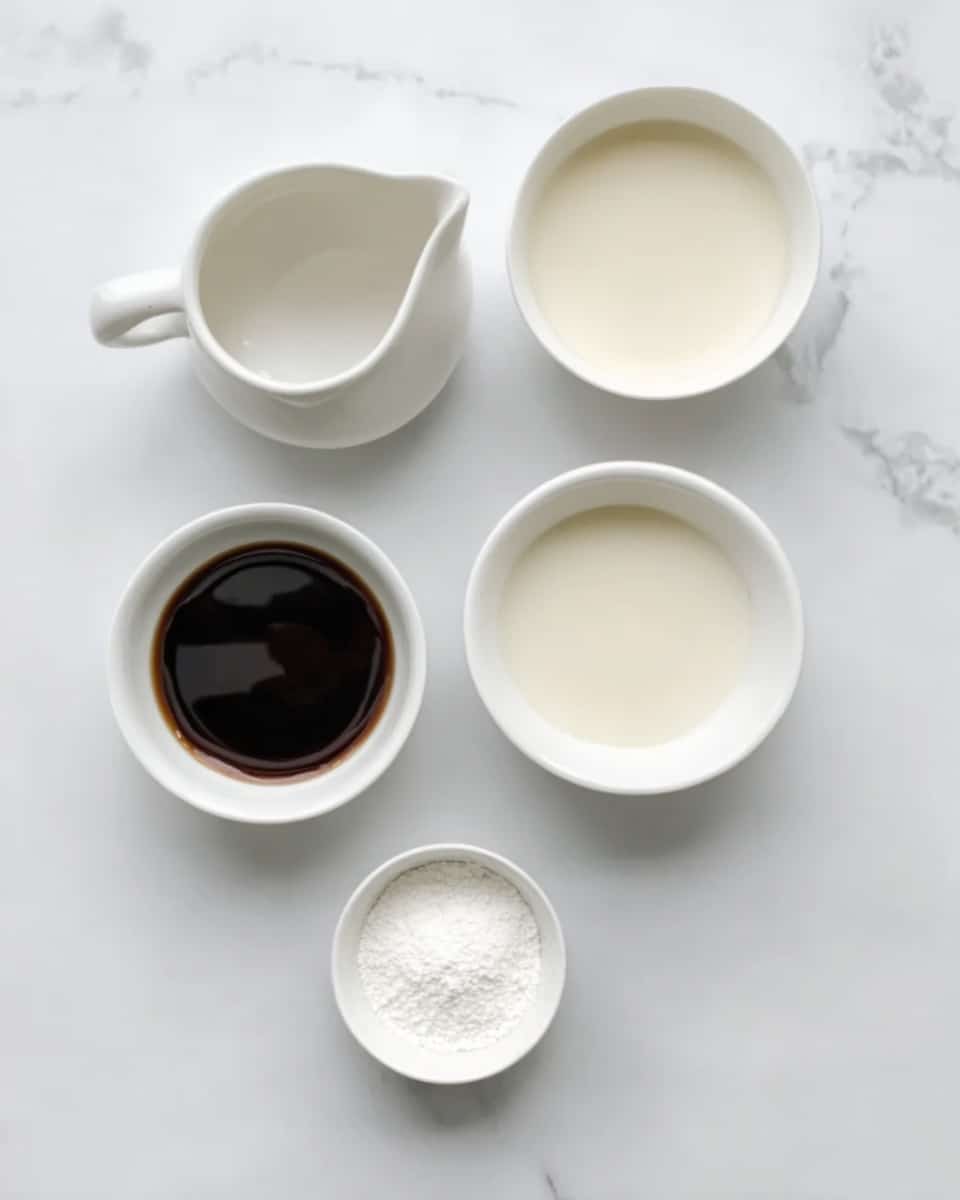 The image shows five white bowls with different liquids and powders arranged on a white marbled surface. The top left bowl is empty and has a handle, the top middle bowl has a small amount of a light creamy liquid, the top right bowl is filled with a slightly thicker light cream liquid, the bottom left bowl holds a small amount of dark brown thick liquid, and the bottom middle bowl contains a white powder. All bowls are simple and clean, contrasting with the smooth white marble surface. Photo taken with an iphone --ar 4:5 --v 7