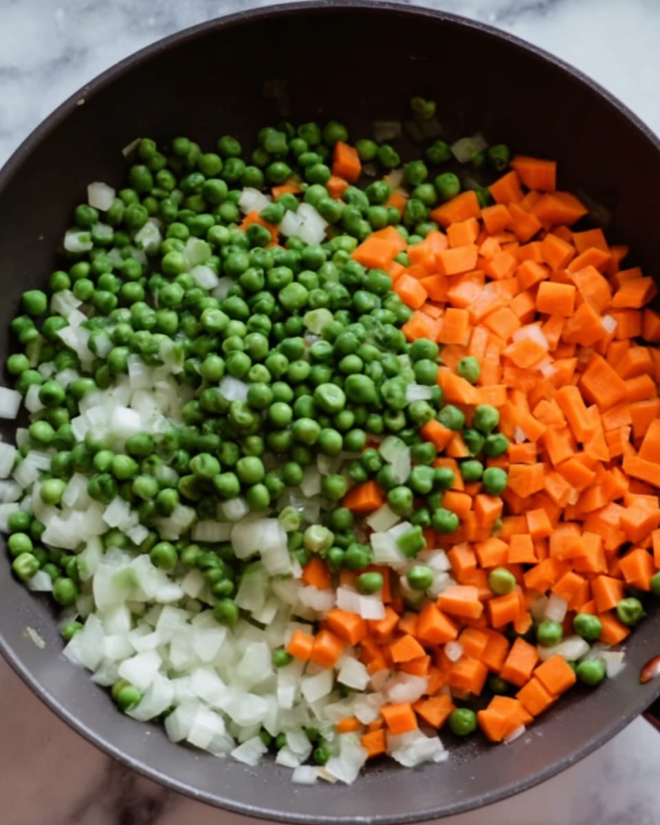 A close-up view of a pan with three layers of chopped vegetables. The bottom layer is small pieces of white onion, scattered evenly. On top of that is a layer of bright orange carrot pieces, cut into small cubes and spread broadly. The top layer features many whole green peas, round and fresh-looking, scattered mostly over the carrots. The pan is dark gray and sits on a surface with a white marbled texture. Photo taken with an iphone --ar 4:5 --v 7