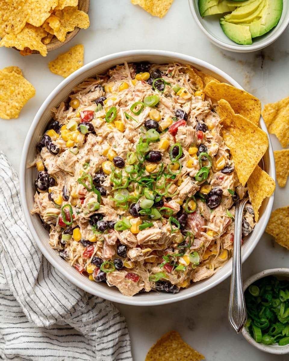A close-up of a burrito cut in half on a white plate with a white marbled background. The burrito has a soft, lightly toasted tortilla wrap with small brown spots. Inside, there are three main layers: a top layer of dark black beans, a middle layer of yellow corn kernels, and a creamy mix of shredded chicken with small red and green vegetable pieces, possibly bell peppers and scallions. A woman's hand is holding one half of the burrito. On the plate beside the burrito are lime wedges and some sliced green scallions scattered around. Photo taken with an iphone --ar 4:5 --v 7