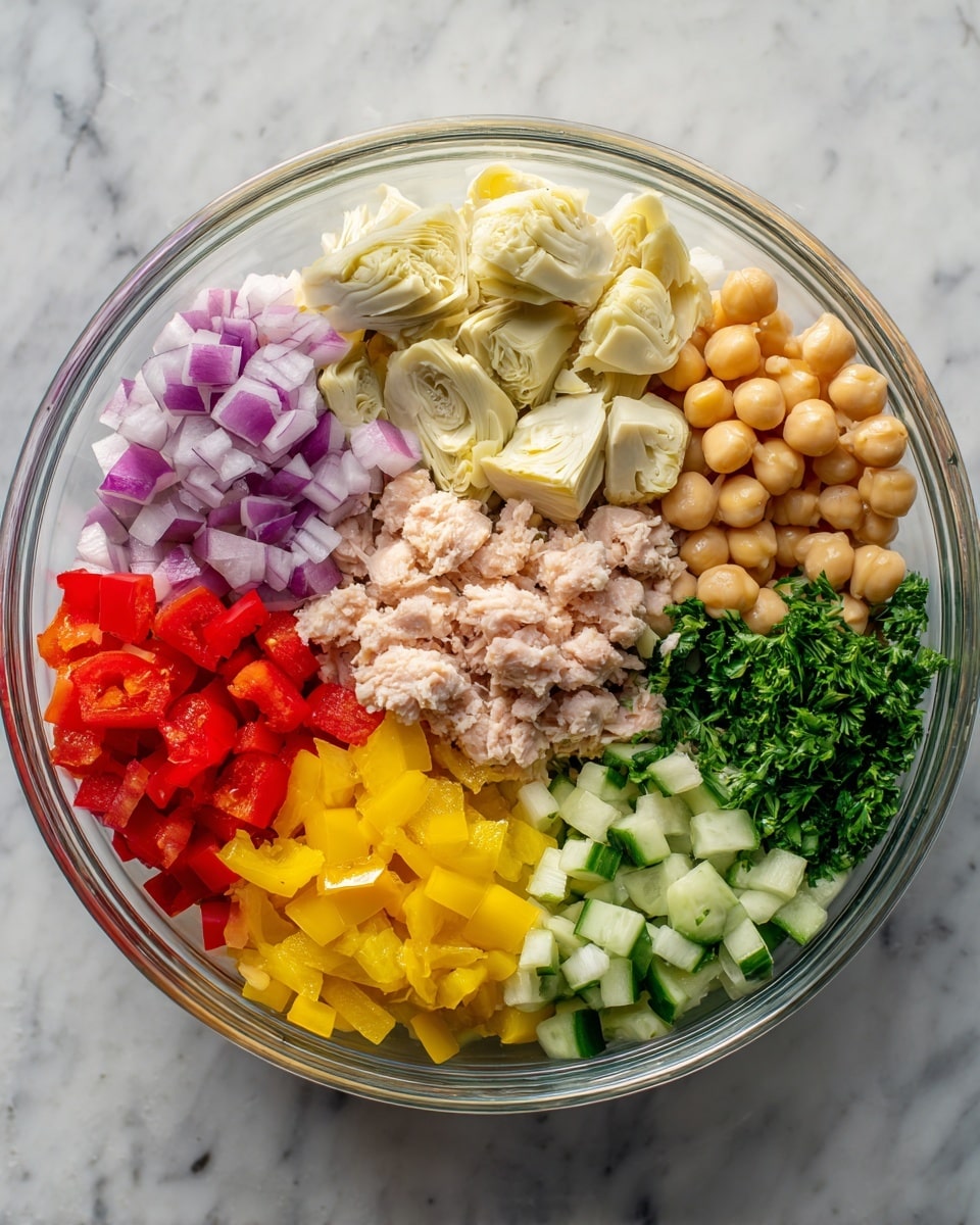 A clear glass bowl sits on a white marbled surface, filled with seven visible layers of ingredients arranged side by side without mixing. At the center top, cream-colored artichoke pieces with a soft texture are placed next to diced purple onions on the right. Below the onions are small cubes of pale green cucumber. In the bottom right corner, smooth and round beige chickpeas fill the space. Next to them is a chunk of light pink, flaky tuna in the middle. Below the tuna, bright yellow pepper rings form a neat row. To the left of the peppers, diced bright red bell pepper pieces sit next to a bunch of finely chopped deep green parsley on the far left side. photo taken with an iphone --ar 4:5 --v 7