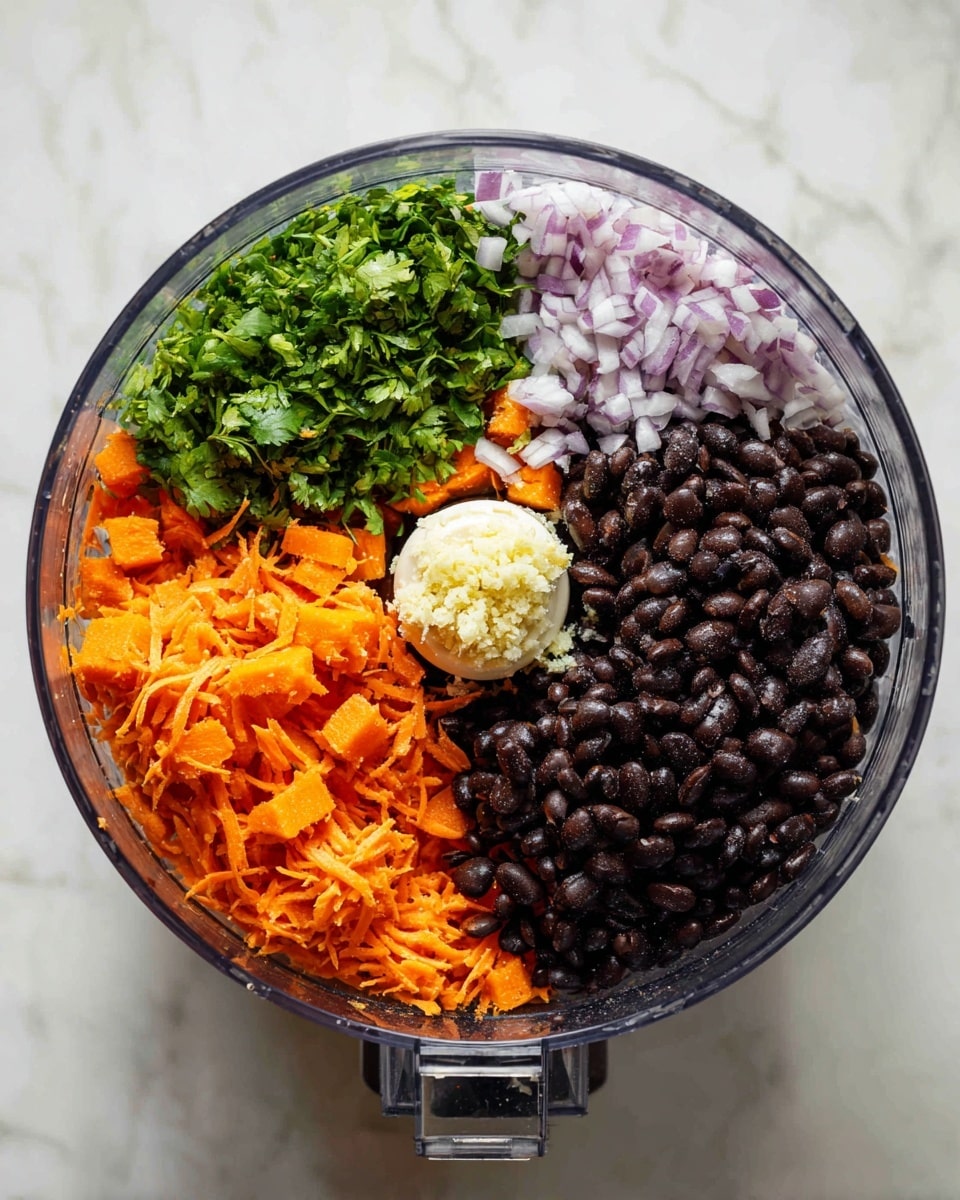 This top-down image shows a clear food processor bowl with five layers of ingredients inside, divided into sections. At the bottom right inside the bowl are dark black beans with a smooth, shiny texture. Above the black beans, there is a layer of finely chopped pale purple onions, next to a small mound of finely minced garlic that is off-white in color. To the top left, there is a fresh green herb, likely cilantro, with leafy texture, and below that, a layer of small orange chunks that look like cooked sweet potato pieces. The largest section, bottom right, has shredded orange carrots with a slightly rough texture. The bowl sits on a white marbled surface. Photo taken with an iphone --ar 4:5 --v 7