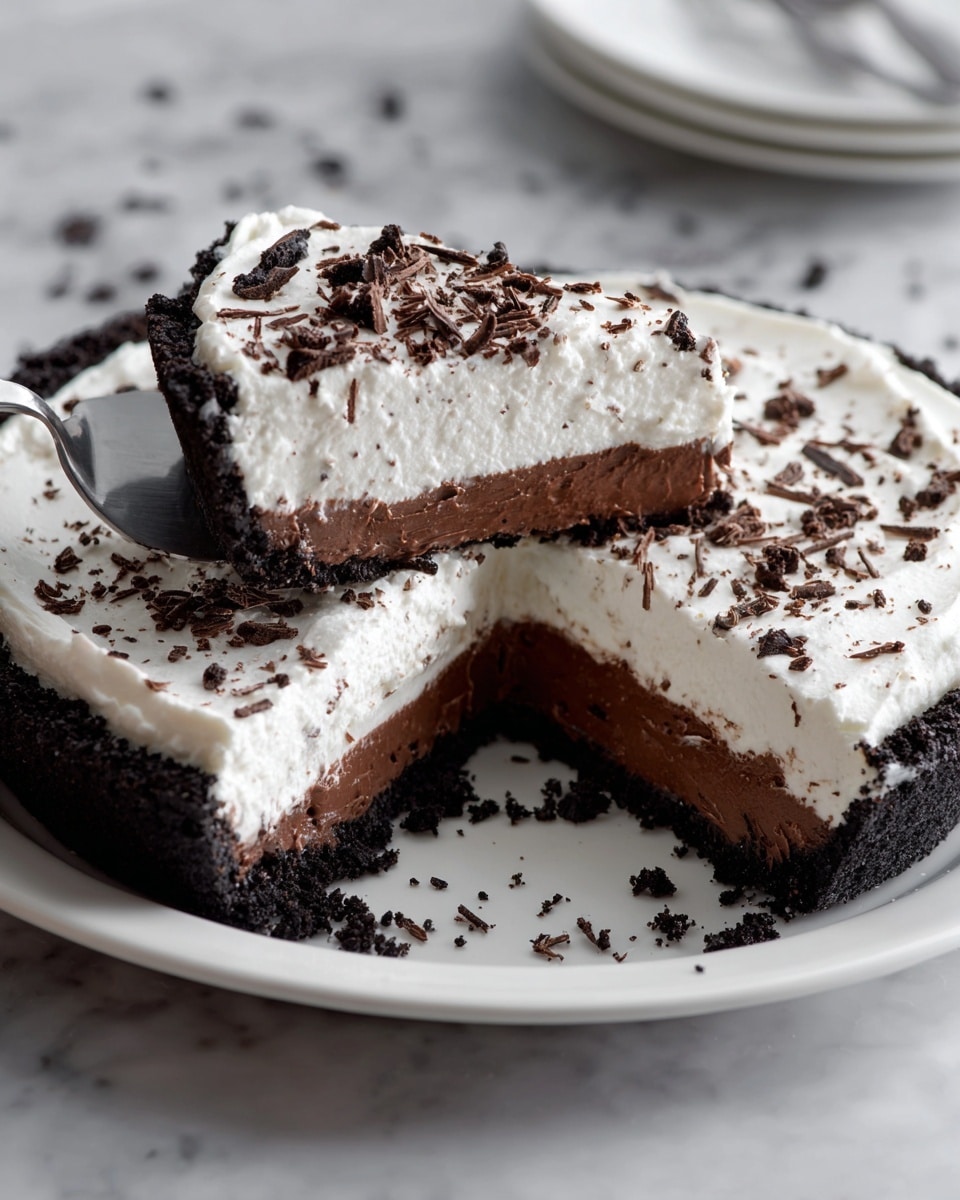 A slice of layered dessert is shown on a white plate with small speckles and a yellow dotted pattern near the edge, set against a white marbled texture. The bottom layer is a dark, crumbly chocolate crust. Above it, the middle layer is a rich, dense, and smooth dark chocolate filling. The top layer is thick, fluffy, and white, covered with dark chocolate shavings scattered unevenly. The edge of the dessert has a border of crushed dark crumbs pressing against the white topping. Photo taken with an iphone --ar 4:5 --v 7