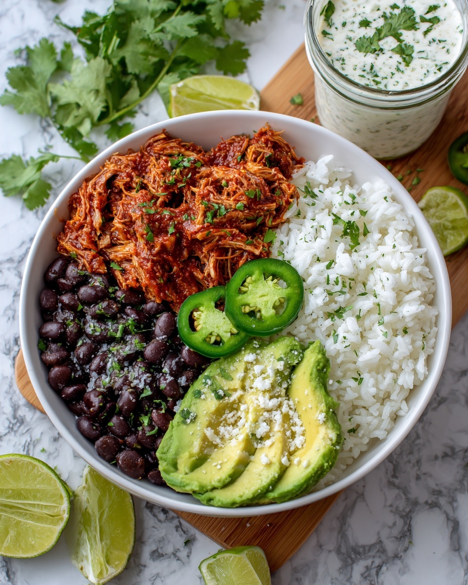 A white bowl filled with four layers: at the bottom, black beans on the left with a dark shiny texture; next to it is a layer of reddish shredded meat in sauce with a chunky look; white fluffy rice sits on the top right, sprinkled with small green cilantro leaves; green jalapeño slices are placed on top of the rice; three slices of light green avocado with a smooth texture are on the bottom right of the bowl, sprinkled with white crumbly cheese; two lime wedges with a shiny juicy inside are positioned on the left rim of the bowl. The bowl sits on a white marbled surface with some green cilantro sprigs nearby and a wooden board holding a jar of white creamy sauce with green flecks, some jalapeño slices beside it. Photo taken with an iphone --ar 4:5 --v 7
