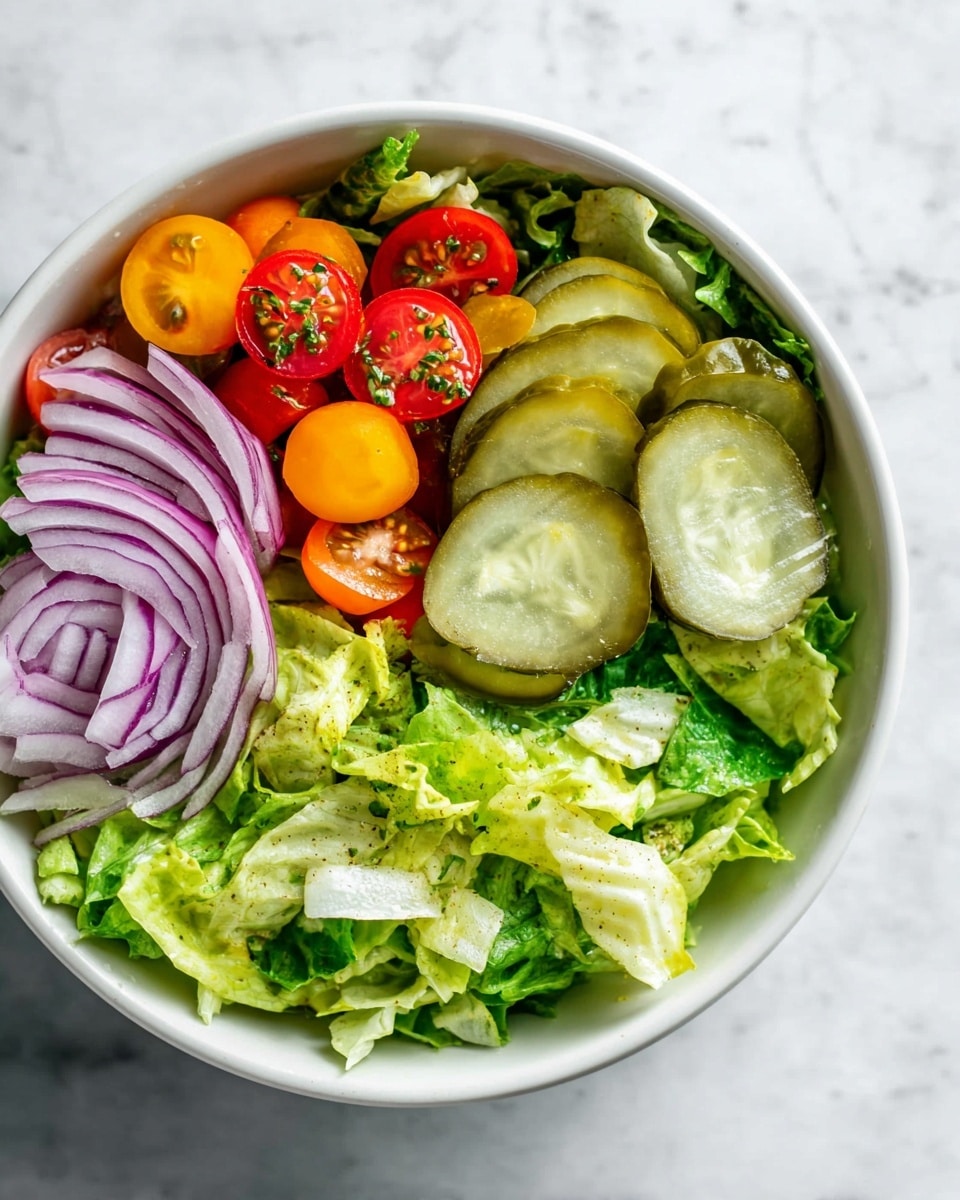 The image shows a fresh salad in a white bowl on a white marbled surface. The bottom layer is made of bright green chopped lettuce with varied shades and textures. On top, there are four thick pickle slices arranged to one side. Next to the pickles are halved cherry tomatoes in red and orange colors with some small green herb sprinkles. At the edge of the bowl, thin rings of purple onion add color contrast. The whole salad looks crisp and colorful. photo taken with an iphone --ar 4:5 --v 7