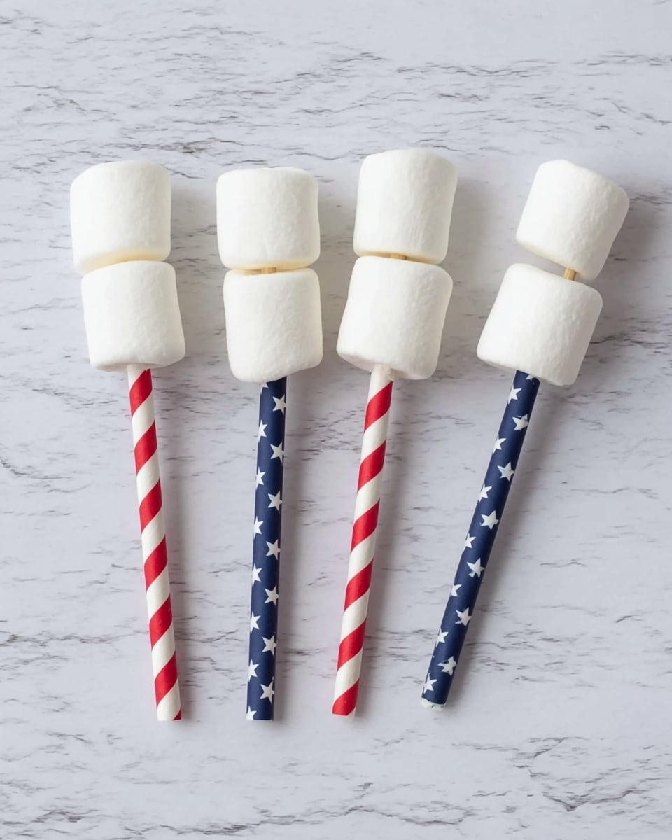 The image shows four sticks laid on a white marbled surface, each with three large, soft, white marshmallows threaded on top. The sticks are decorated with patriotic patterns: two sticks have red and white stripes, while the other two have dark blue with white stars. The marshmallows are evenly spaced and aligned vertically on each stick, creating a simple but festive look. photo taken with an iphone --ar 4:5 --v 7