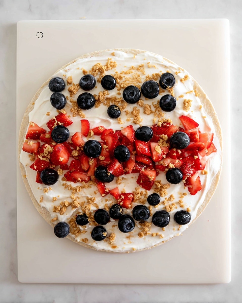 A round tortilla lays flat on a white cutting board with a spread of white cream on top as the first layer. The second layer is made of small pieces of fresh strawberries, cut into small chunks, scattered mainly in the lower half of the tortilla. On top of and around the strawberries, whole and halved blueberries are placed evenly across the top half of the tortilla. Crumbled light brown cookie bits are sprinkled in a rough line near the top edge of the tortilla. The overall look is colorful with reds, blues, and light brown on the white cream and tortilla, set against a white marbled surface. Photo taken with an iphone --ar 4:5 --v 7