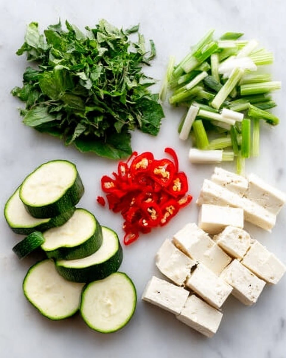 The image shows six groups of fresh ingredients neatly arranged on a white marbled surface. In the top left, there is a bunch of green leafy herbs with fine leaves. To the right of the herbs, there are chopped green onion stalks with white bases. Further right, there are white rectangular pieces, sliced evenly. At the bottom left, there are green zucchini slices, showing the light green inside and dark green skin. In the center, there are bright red chili pepper slices, cut into small segments. Finally, to the right bottom corner, there are tofu cubes, showing a soft white texture with a few black pepper specks on top. photo taken with an iphone --ar 4:5 --v 7