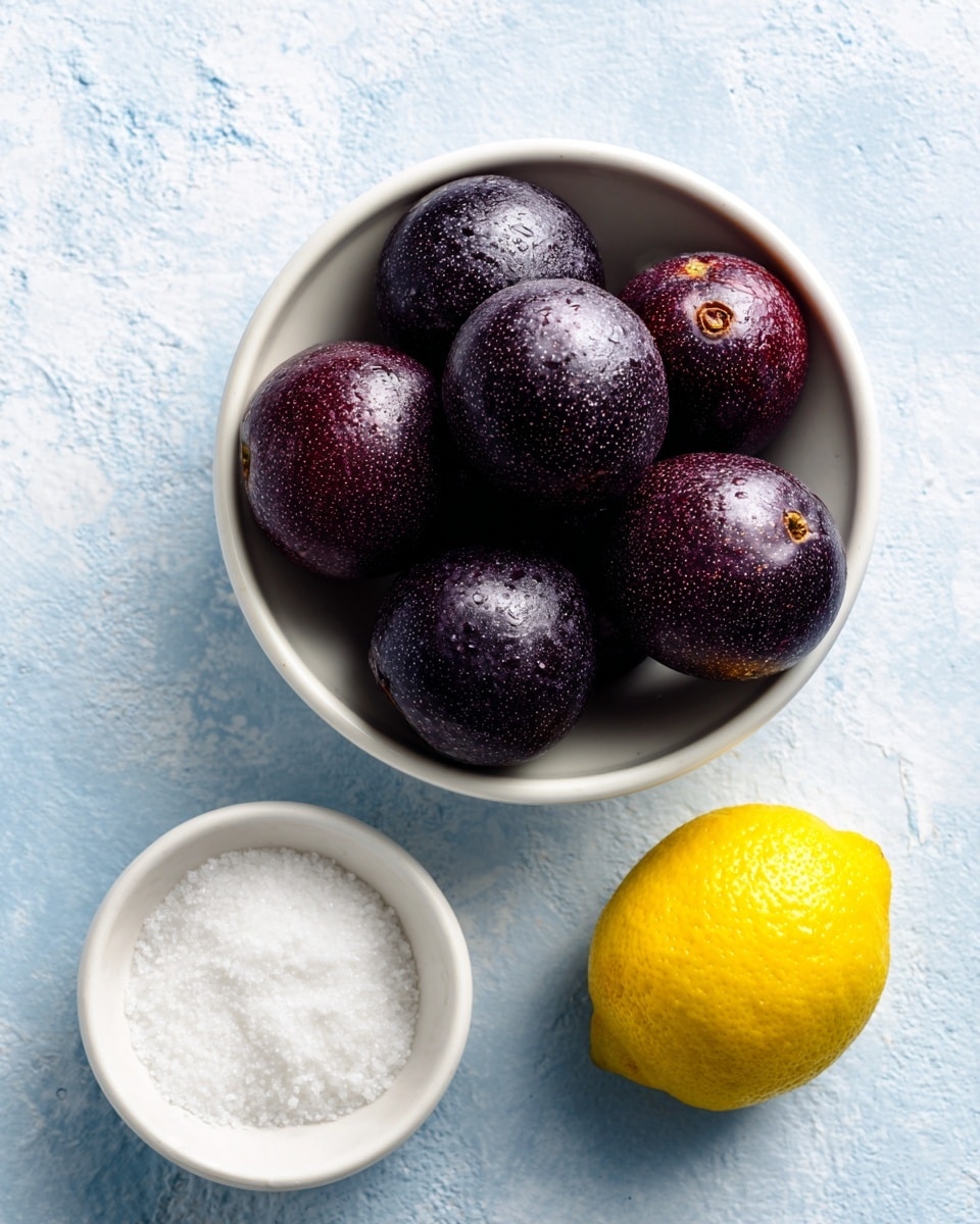A white bowl holds eight dark purple passion fruits with a slightly wrinkled texture, placed in a loose pile at the center of the image on a white marbled surface. Below it, a small white bowl filled with fine white caster sugar is positioned to the left, while to the right, a bright yellow lemon sits directly on the surface. The background is a soft blue color with a subtle textured appearance. photo taken with an iphone --ar 4:5 --v 7