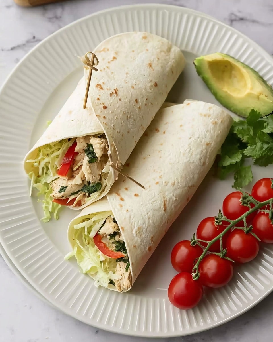 Two wraps made with white soft tortillas are placed on a white plate with small ridges. Each wrap has three layers inside: light green shredded lettuce at the bottom, pieces of chicken with green herbs in the middle, and thin slices of red bell pepper on top. One wrap is closed and held with a small wooden skewer, and the other is partly open, showing the filling clearly. A small wedge of green avocado and some green cilantro leaves sit behind the wraps on the plate, and a bunch of four bright red cherry tomatoes on the vine is placed to the right side of the plate. The plate rests on a white marbled surface. photo taken with an iphone --ar 4:5 --v 7