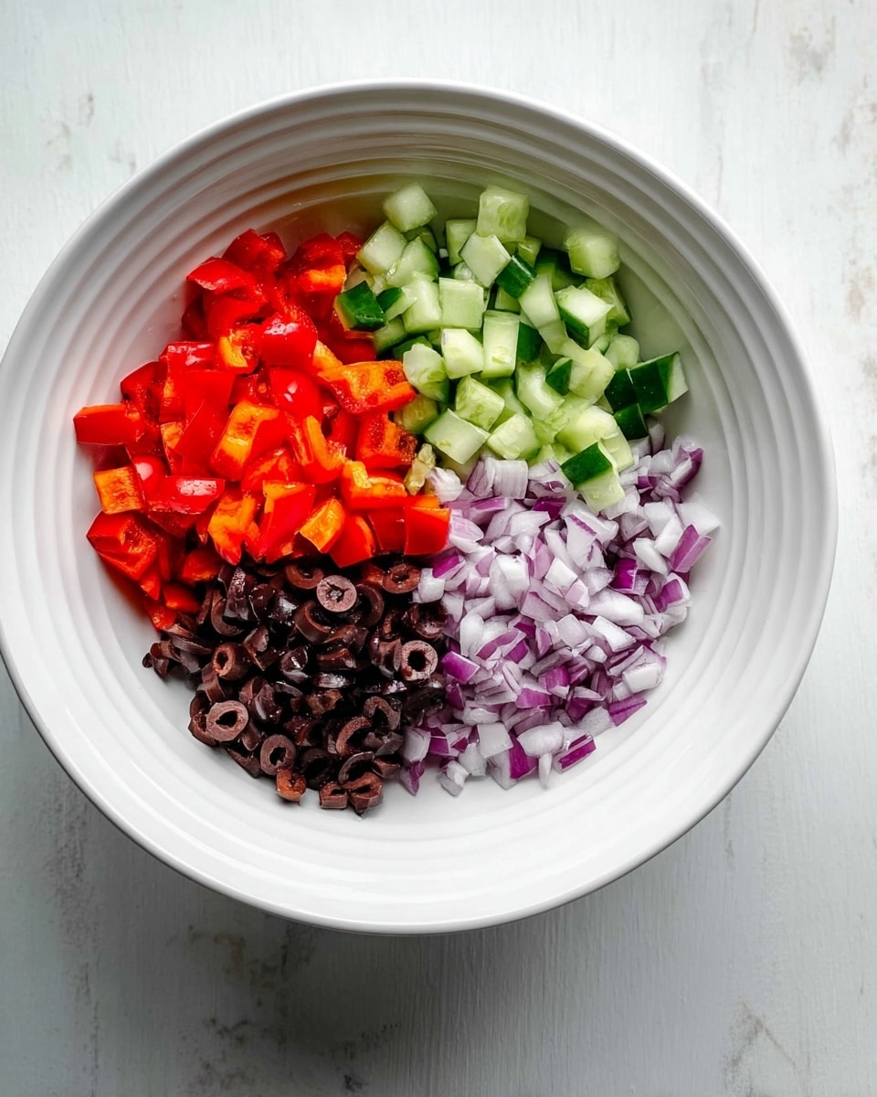 Inside a large white bowl, there are four sections of diced ingredients neatly arranged. Starting from the top left and moving clockwise, there is a layer of bright red diced bell pepper, followed by a layer of small green cucumber chunks. Next, there is a section of finely chopped purple and white onions, and finally, a bottom left section filled with small dark brown sliced olives. The bowl sits on a white marbled surface. photo taken with an iphone --ar 4:5 --v 7