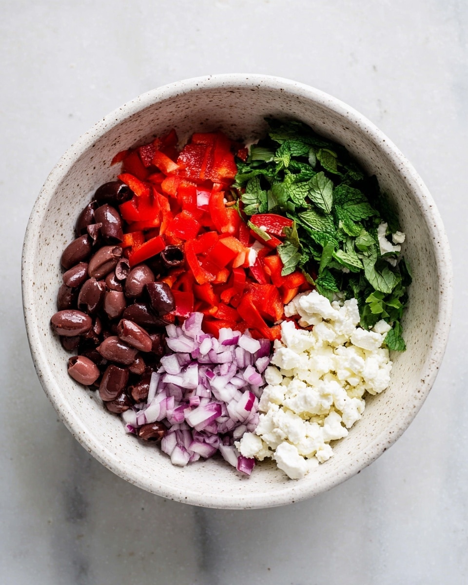 A white speckled bowl is filled with five separate layers of ingredients, arranged side by side. Starting from the left, there are dark brown sliced olives with a smooth texture, next to bright red diced bell peppers with a shiny surface. In the middle, fresh green chopped mint leaves add a leafy texture, followed by small purple and white diced pieces of red onion on the right. At the bottom right, there are white crumbled pieces of cheese with a soft, crumbly texture. The bowl sits on a white marbled surface. photo taken with an iphone --ar 4:5 --v 7