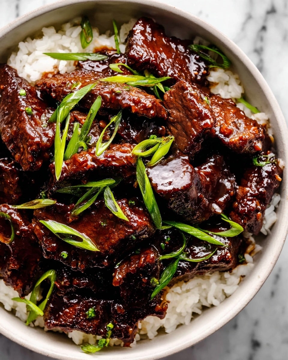 A white bowl filled with a layer of white rice at the bottom, topped with many pieces of dark brown beef covered in a glossy, thick sauce. The beef pieces have a rich, shiny texture and are scattered unevenly. Bright green onion slices are sprinkled on top, adding fresh color contrast to the dark beef. The bowl sits on a white marbled surface. Photo taken with an iphone --ar 4:5 --v 7