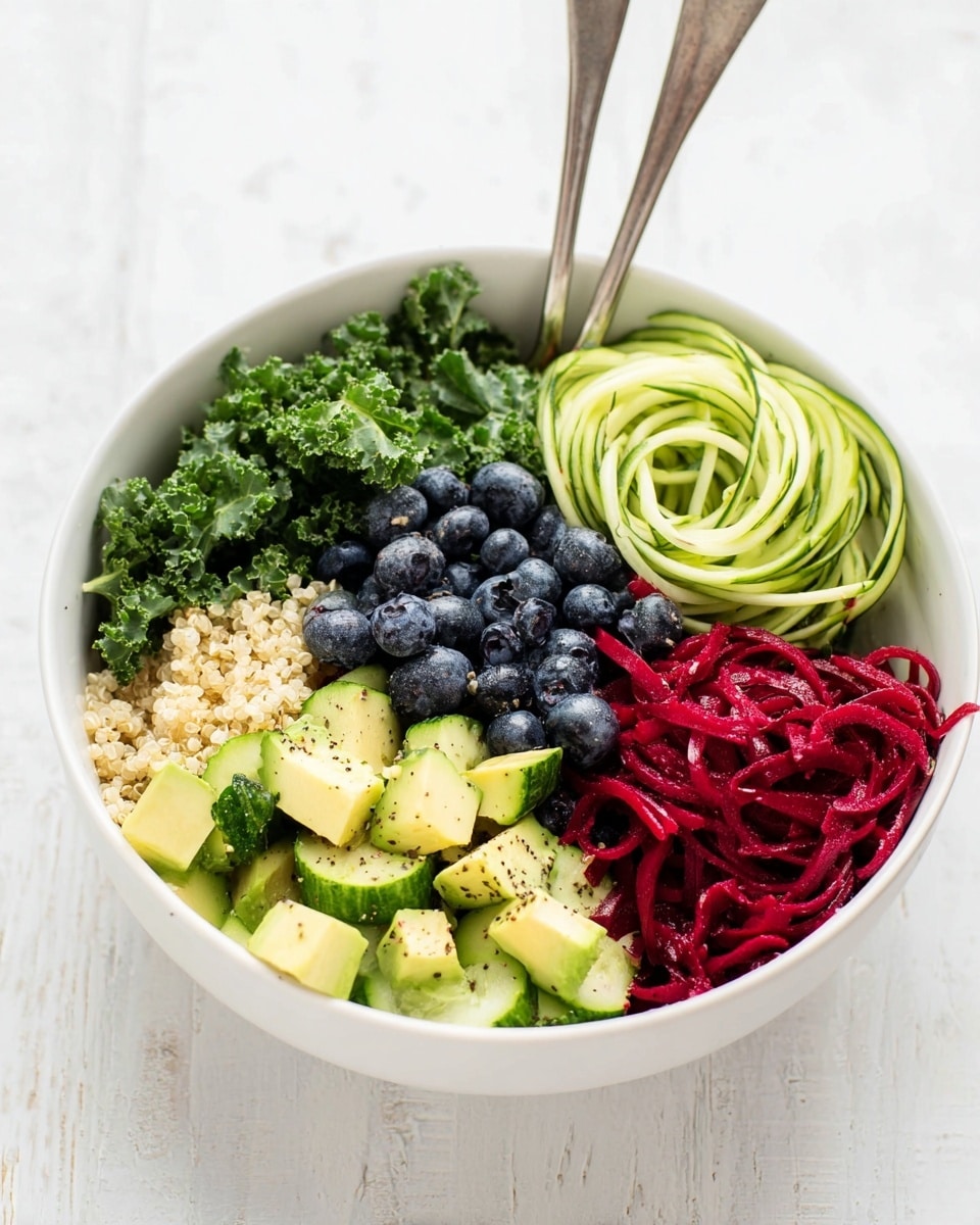 A white bowl holds a colorful salad with six layers visible from left to right: dark green curly kale leaves, bright green cucumber cubes with black pepper sprinkled, deep red spiral-shaped beet noodles, pale green avocado chunks mixed with light beige quinoa grains, and a cluster of dark blue blueberries. Two forks are placed inside the bowl at opposite edges. The bowl sits on a white marbled surface, creating a clean and fresh look. photo taken with an iphone --ar 4:5 --v 7