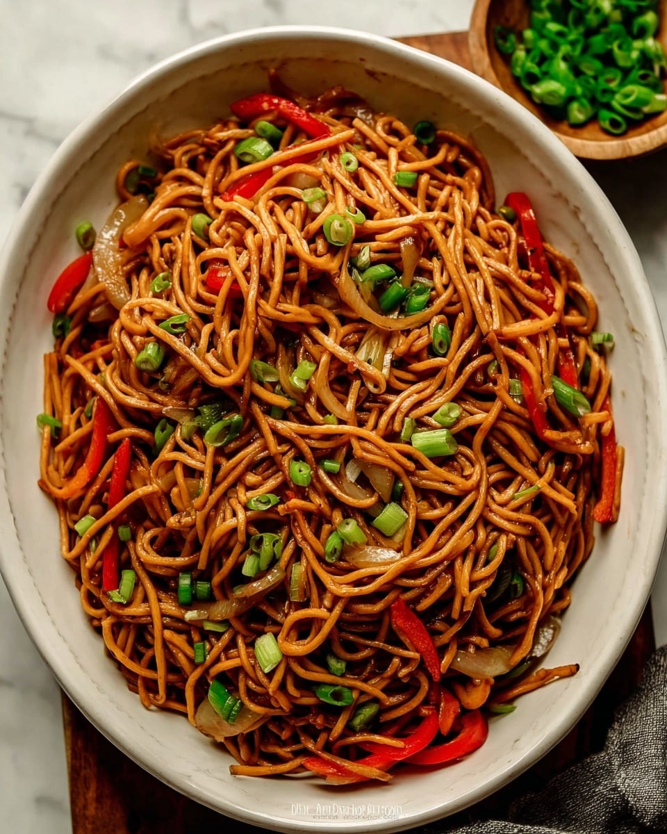 A white bowl full of cooked brown noodles tossed with red bell pepper strips and light-colored onion pieces. The noodles have a shiny texture, showing a light sauce coating, and bright green chopped scallions are scattered on top. The bowl sits on a white marbled surface with a small wooden bowl filled with more scallions in the top right corner. Photo taken with an iphone --ar 4:5 --v 7