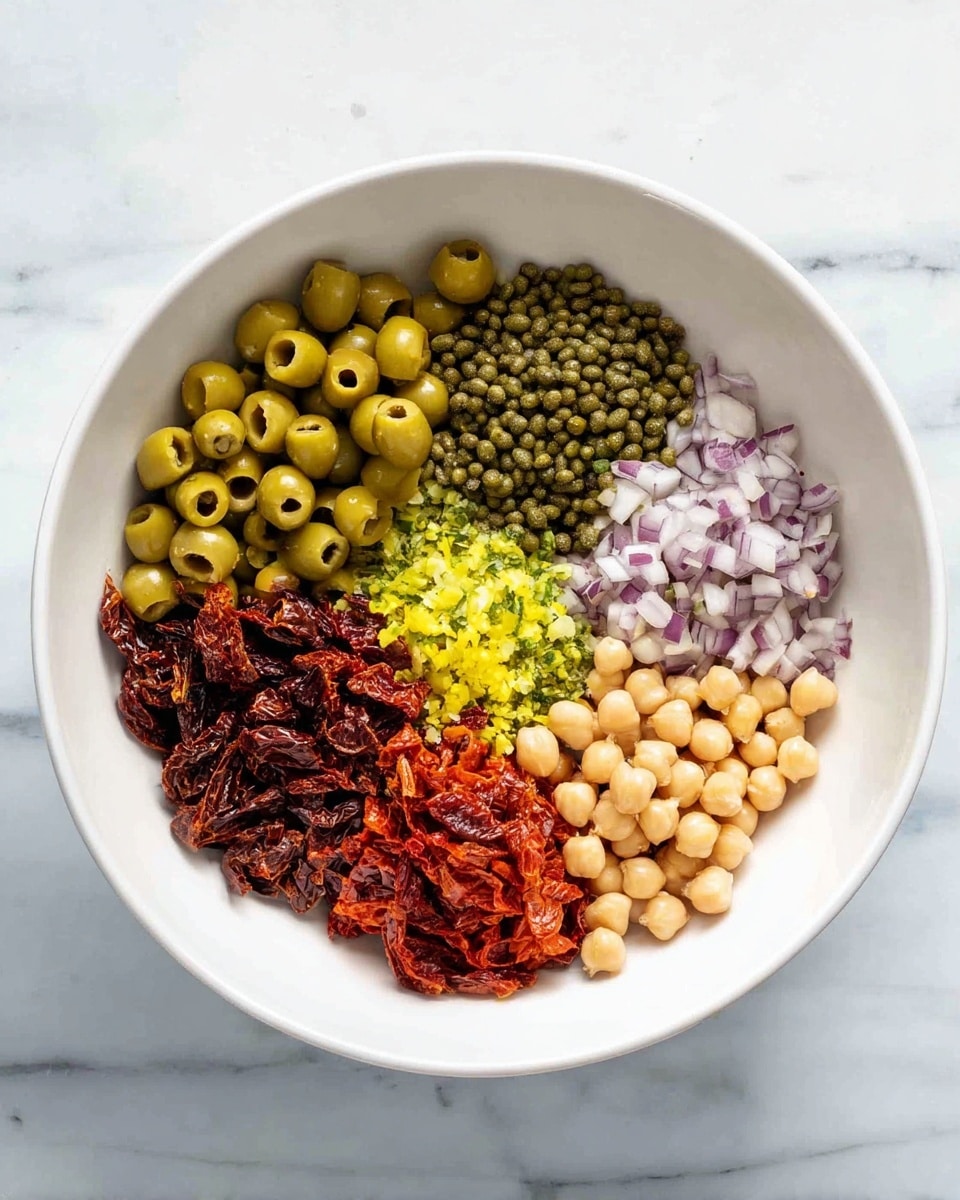 A white bowl is filled with six separate piles of ingredients, each taking up roughly equal space along the inside of the bowl. Starting from the top center and going clockwise, there is a cluster of bright green sliced olives with a smooth, shiny texture. Next to the olives is a pile of small, dark green capers with a slightly bumpy texture. Moving down, there is a heap of finely chopped pale purple shallots. Below the shallots, there is a pile of finely chopped bright yellow pepper pieces. To the left of the peppers, deep red sun-dried tomato pieces with a wrinkled texture fill the space. Lastly, next to the sun-dried tomatoes and below the olives, there is a pile of round, pale beige chickpeas with a smooth surface. The bowl rests on a white marbled surface. photo taken with an iphone --ar 4:5 --v 7