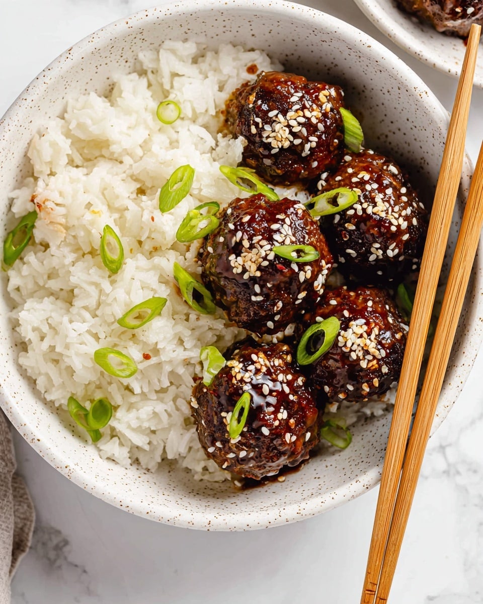 In a white speckled bowl on a white marbled surface, there is a layer of fluffy white rice covering half the bowl, topped with a few small green onion slices; the other half holds six dark brown glossy meatballs glazed with sauce, each sprinkled with white sesame seeds and garnished with small slices of green onion. A pair of light wooden chopsticks rests across the bottom edge of the bowl. Photo taken with an iphone --ar 4:5 --v 7