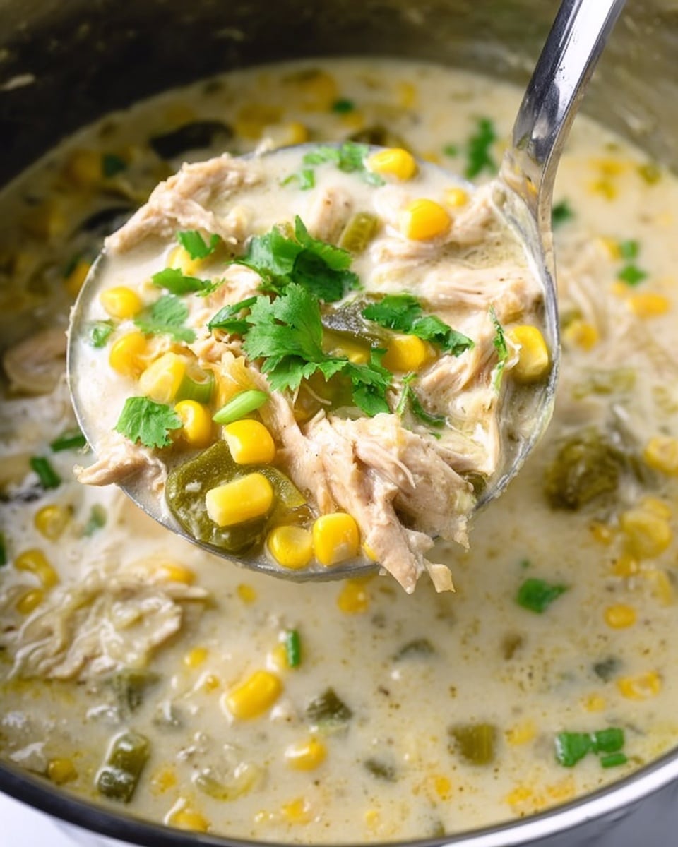 A close-up view of a thick creamy soup filled with several layers: the base is a light creamy broth with a smooth texture, mixed with chunks of shredded light beige chicken, bright yellow corn kernels, and pieces of green onions scattered throughout. On top, a garnish of fresh green cilantro leaves adds a pop of color. The soup is held in a large silver ladle above the pot, showing the vibrant mix of ingredients. The background is a white marbled texture photo taken with an iphone --ar 4:5 --v 7