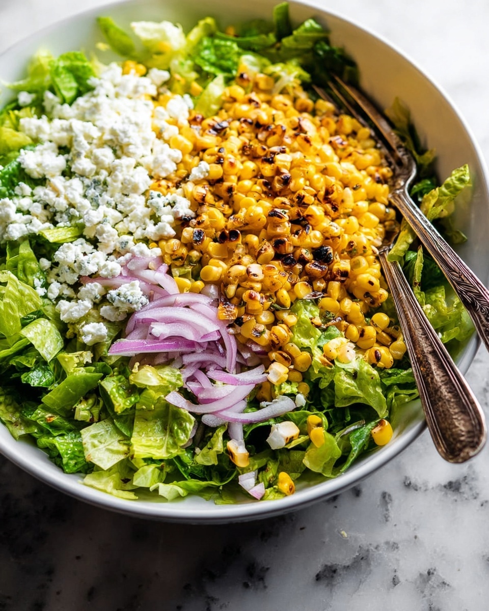 A white bowl filled with a fresh salad is shown on a white marbled surface. The salad has four layers: the bottom layer is bright green chopped lettuce, the left side has crumbled white cheese, the top right has thinly sliced light purple onion rings, and the center is a heap of golden yellow grilled corn with some brown charred spots. Two rustic silver forks are placed diagonally on opposite sides of the bowl, partially resting on the salad. Photo taken with an iphone --ar 4:5 --v 7
