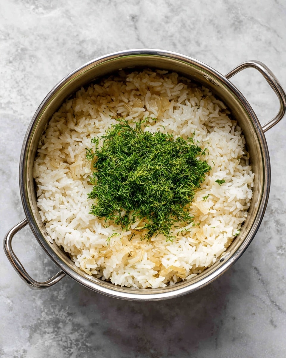 A round metal pot filled with cooked white rice mixed with small pieces of translucent cooked onions forms the base layer, which has a soft and fluffy texture. On top in the center, there is a small pile of finely chopped bright green fresh dill, adding a fresh and leafy texture. The pot has two metal handles on the sides, and it sits on a surface with a white marbled texture. photo taken with an iphone --ar 4:5 --v 7