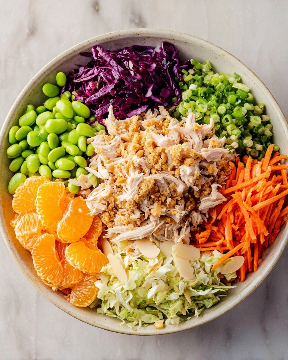 A close-up of a white bowl filled with eight colorful layers arranged in sections: at the bottom right is finely shredded light tan chicken, next to it are thin bright orange carrot sticks, above them long pale cream almond slivers, then bright green edamame beans. Moving clockwise, there are chopped light green scallions, shredded vibrant purple cabbage, bright orange tangerine slices, a large mound of mixed white and brown fried rice in the center with a slightly crispy texture, and shredded pale green cabbage filling the space between the tangerines and chicken. All ingredients are separate but closely packed on a white marbled surface, photo taken with an iphone --ar 4:5 --v 7