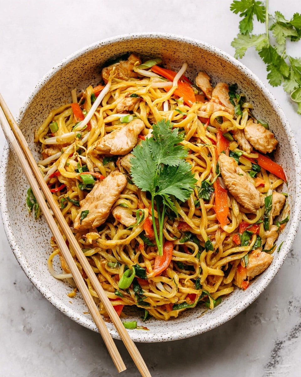A white bowl filled with a mix of yellow noodles, small pieces of cooked light brown chicken, thin orange carrot strips, and green herbs scattered throughout. The dish is topped with a few fresh green cilantro leaves in the center. Light green onion slices and tiny dark green herb bits are spread on top and within the noodles. Two light-colored chopsticks rest diagonally on the bowl's edge. The bowl sits on a white marbled surface with some chopped green onions and cilantro sprigs nearby. photo taken with an iphone --ar 4:5 --v 7