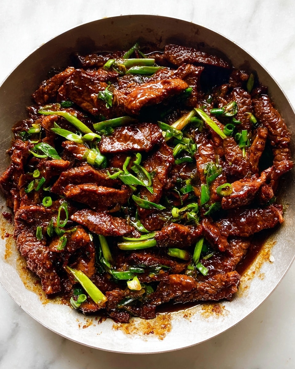 A round pan filled with strips of dark brown cooked meat coated in a shiny, rich sauce mixed with bright green chopped spring onions, placed on a white marbled surface; the meat looks tender and the sauce makes it glisten under the light photo taken with an iphone --ar 4:5 --v 7