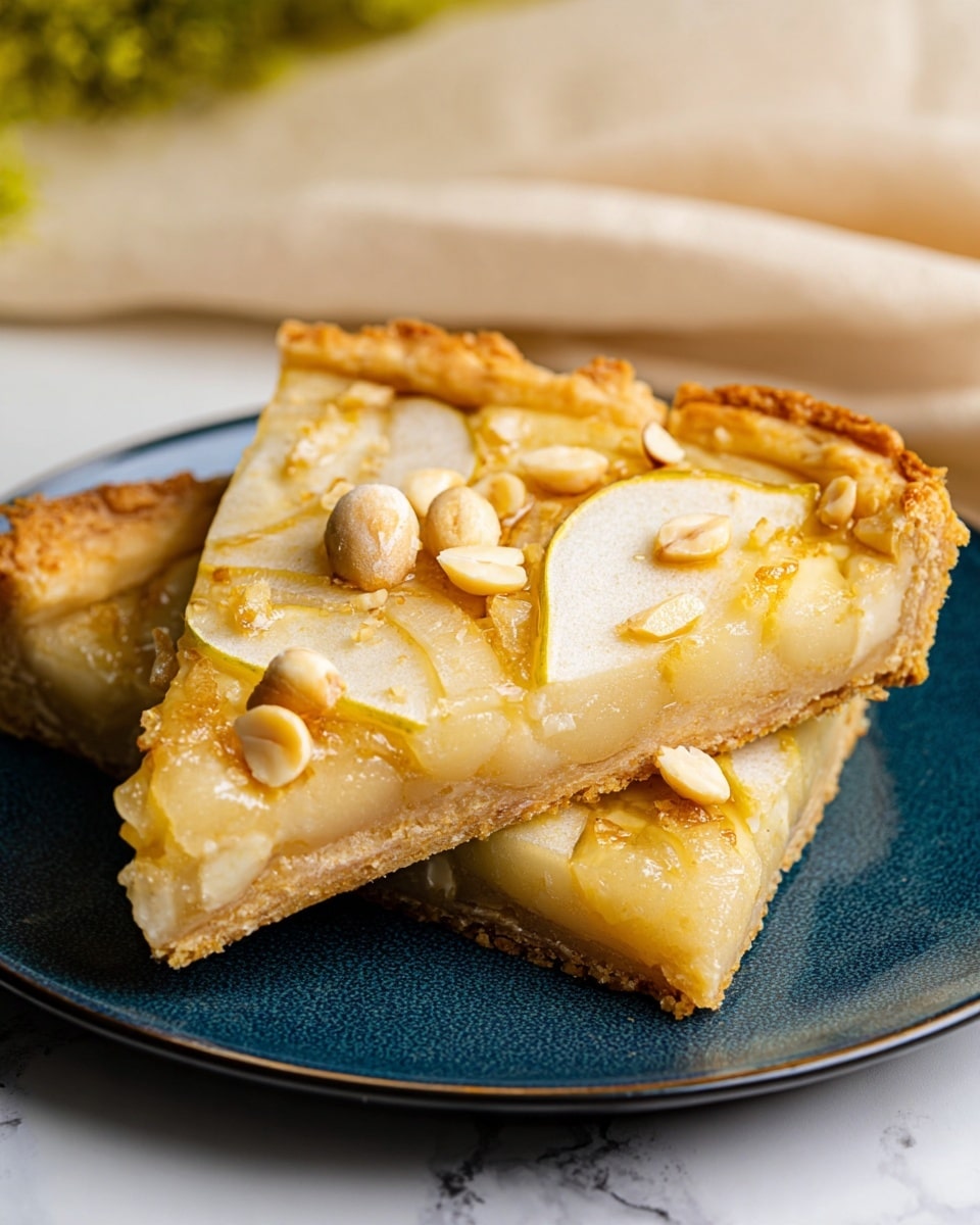 Two slices of fruit tart are stacked on a white plate with a dark blue inner surface. The tart has a thick, golden-brown crust that looks crispy and flaky. On top of the crust, there are thin, light yellow fruit slices arranged in an overlapping pattern. Scattered over the fruit slices are whole and broken pieces of nuts that are light tan in color, adding texture. The tart filling underneath is creamy and pale yellow, visible where the tart edges open slightly. The background is a white marbled surface with soft-focus green and beige accents, and a folded beige cloth is faintly visible. Photo taken with an iphone --ar 4:5 --v 7
