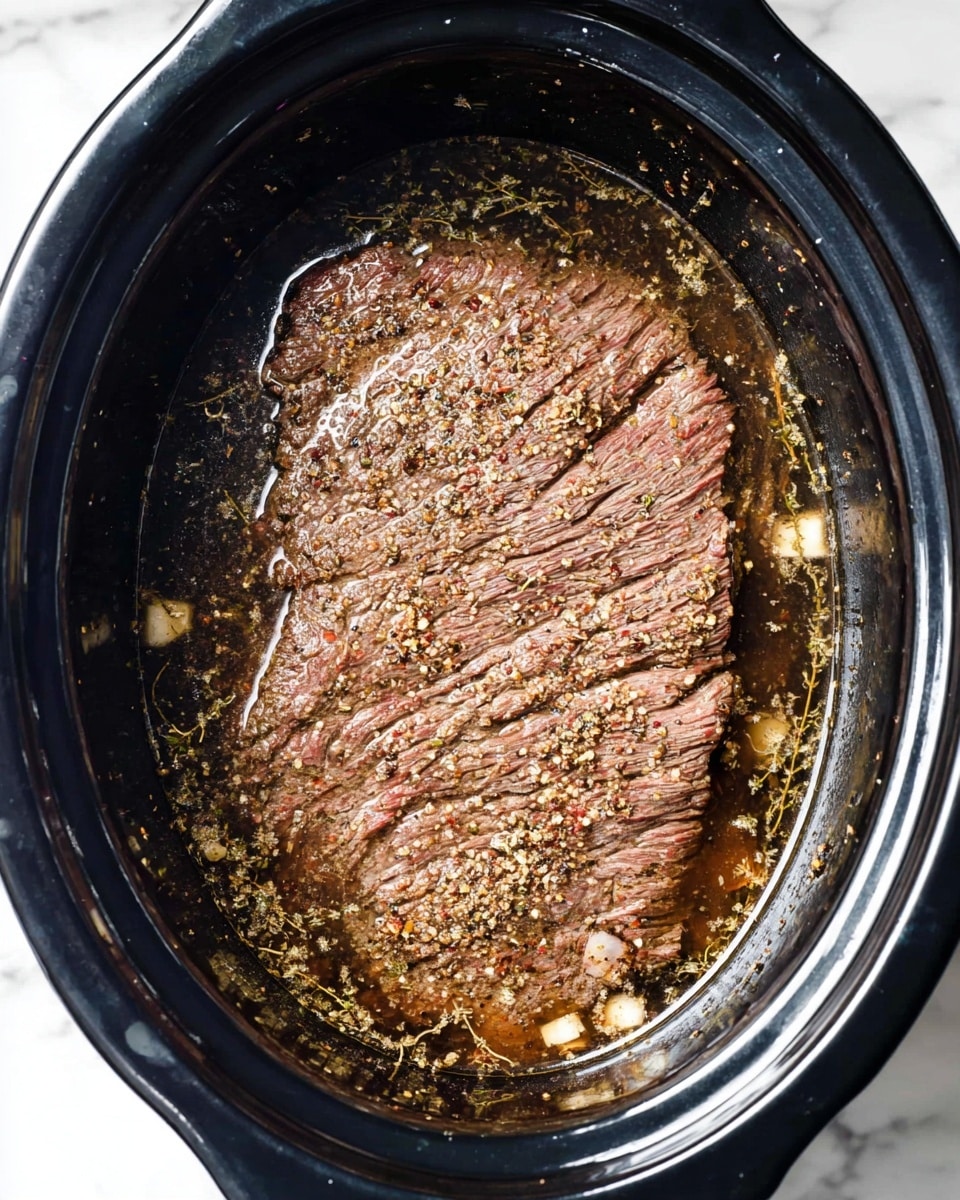 A dark brown cooked meat piece sits in the center of a black slow cooker, surrounded by a watery broth with herbs and small white pieces floating in it. The meat has a textured surface with seasoning sprinkles across the top, showing some natural lines and slight curves. The slow cooker rests on a white marbled surface. photo taken with an iphone --ar 4:5 --v 7