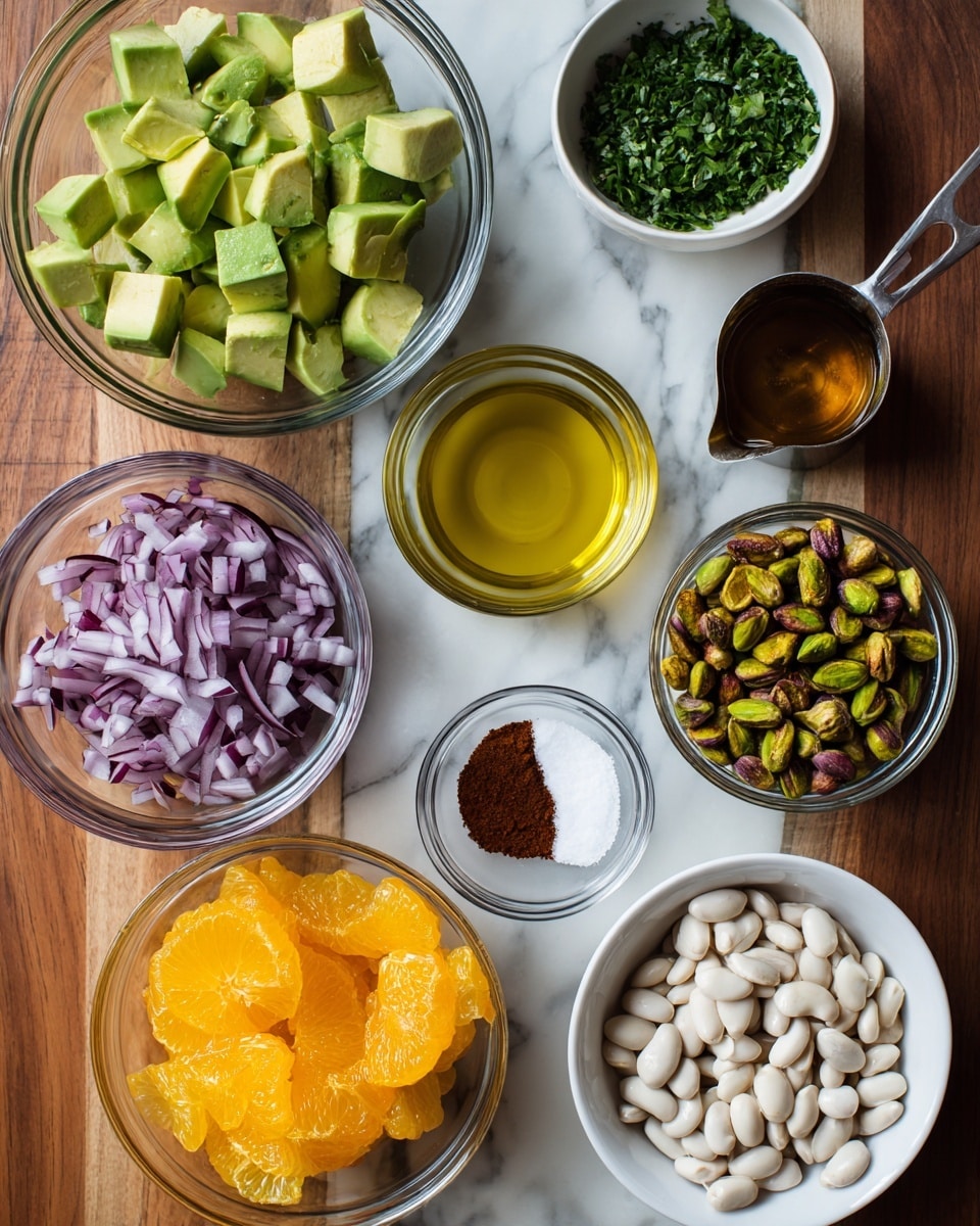 The image shows several small bowls and a measuring cup with different ingredients arranged on a wooden surface changed to a white marbled texture. In the center-left is a clear glass bowl with light green avocado chunks scored with grid lines. To the top right of it is a small white bowl with dark green chopped parsley. Above the avocado is a small metal measuring cup filled with golden olive oil. To the center is a small clear bowl with white salt and a dark reddish-brown powder side by side. To the right of that is a clear glass bowl filled with greenish-brown pistachios. Below the salt and sumac bowl is a white bowl with thinly sliced purple onion strips. At the bottom-left is a white bowl full of glossy white beans. At the bottom-right is a clear glass bowl with bright orange and yellow citrus slices. Near the center-bottom is a small white bowl with reddish-orange citrus juice. Photo taken with an iphone --ar 4:5 --v 7